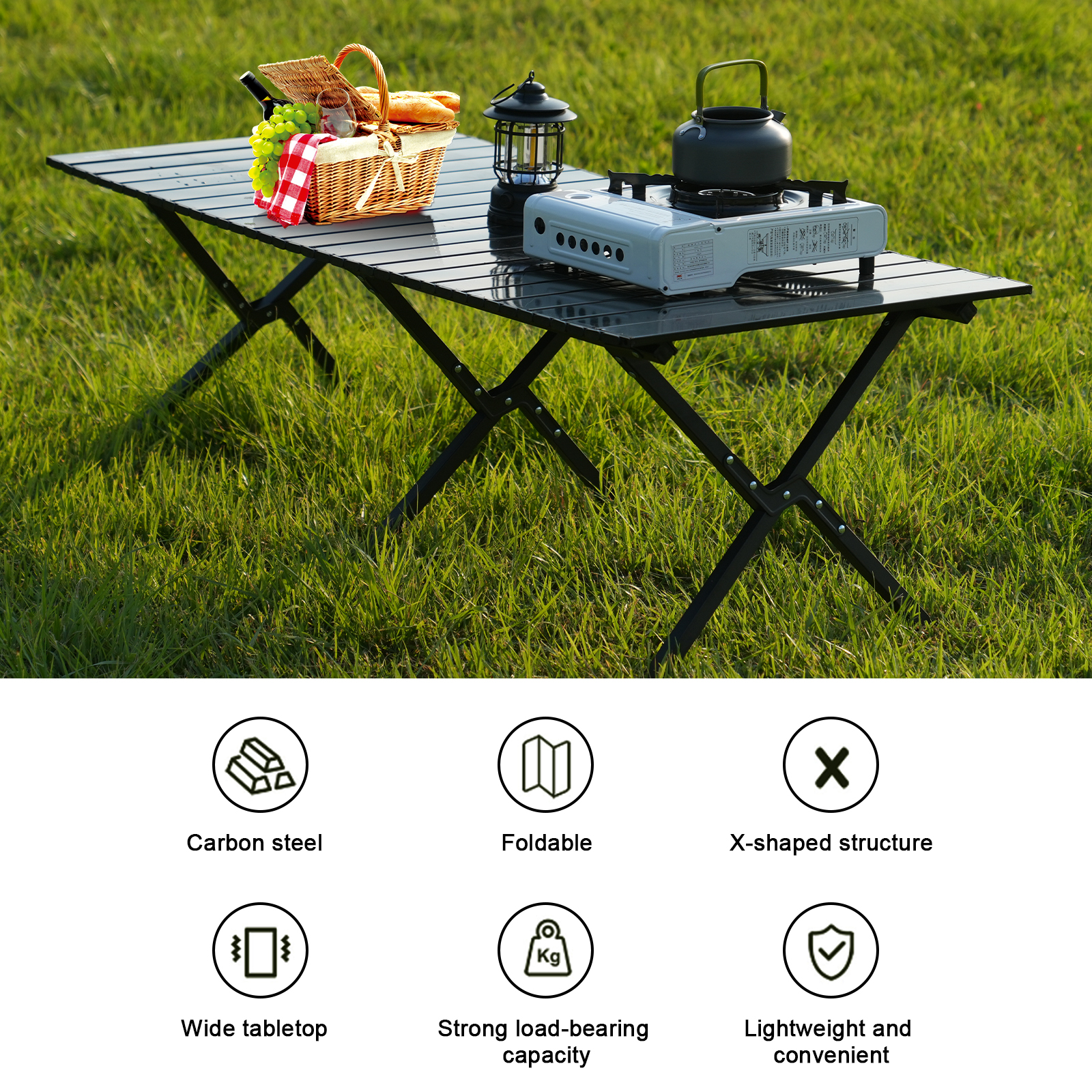 A black folding table with picnic basket, a lantern, and a stove on green grass. Features carbon steel and foldable design.