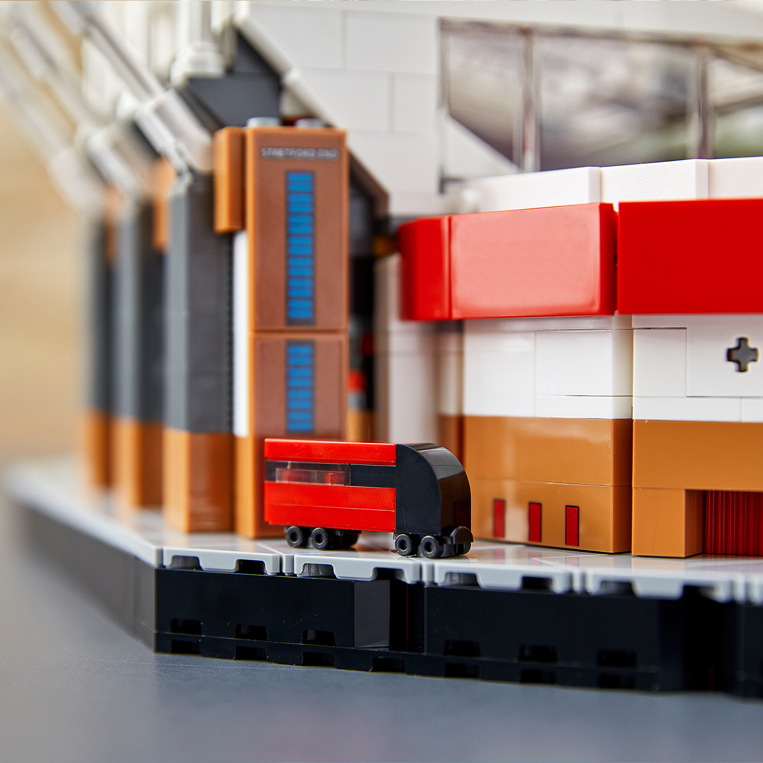 Ön planda kırmızı ve siyah bir tren bulunan bir Lego stadyum modeli. Kahverengi, beyaz ve kırmızı yapı taşları stadyumu oluşturuyor.