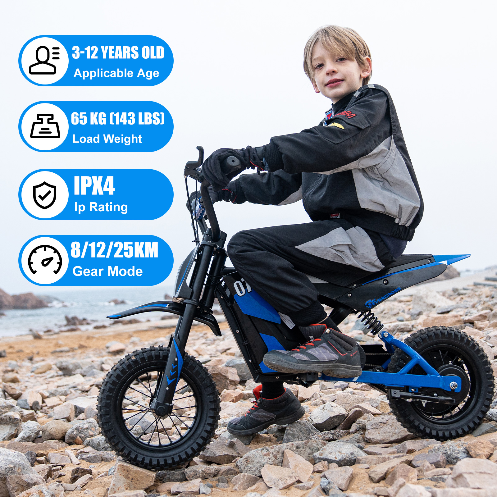 A young boy rides a blue and black electric dirt bike on a rocky terrain. The bike has black tires. The sky is overcast.