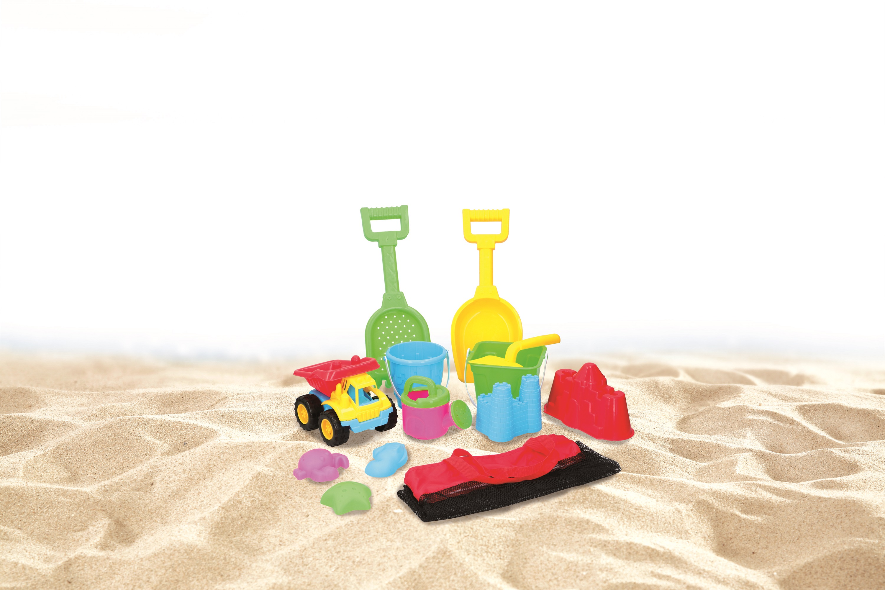 Set di giocattoli da spiaggia sulla sabbia. Include pale, secchi, un camion e stampi. Lo sfondo mostra il mare sfocato.