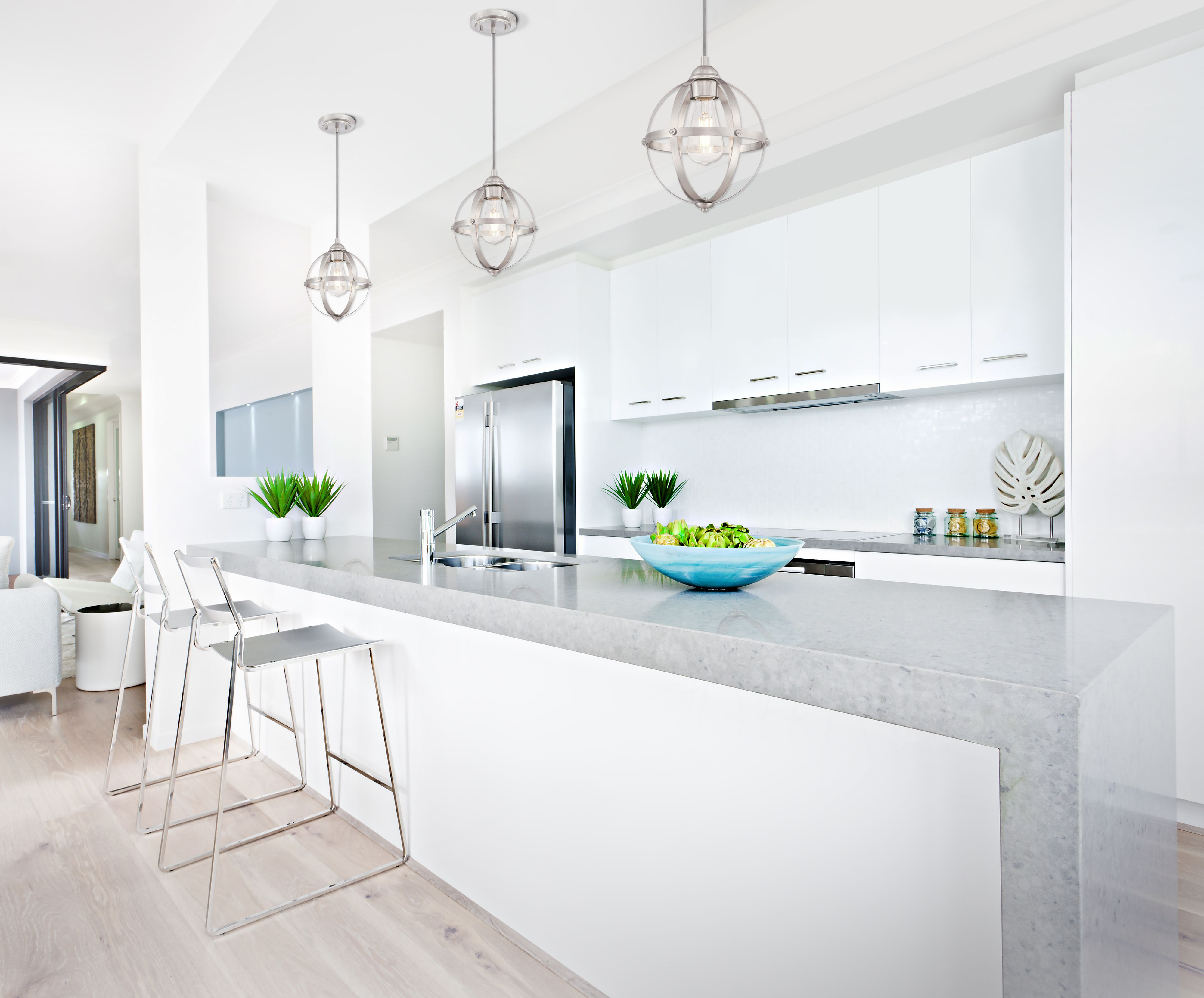 Moderne Küche mit weißen Schränken, einer Marmorarbeitsplatte und drei Pendelleuchten. Inklusive Barhocker und Edelstahlkühlschrank.