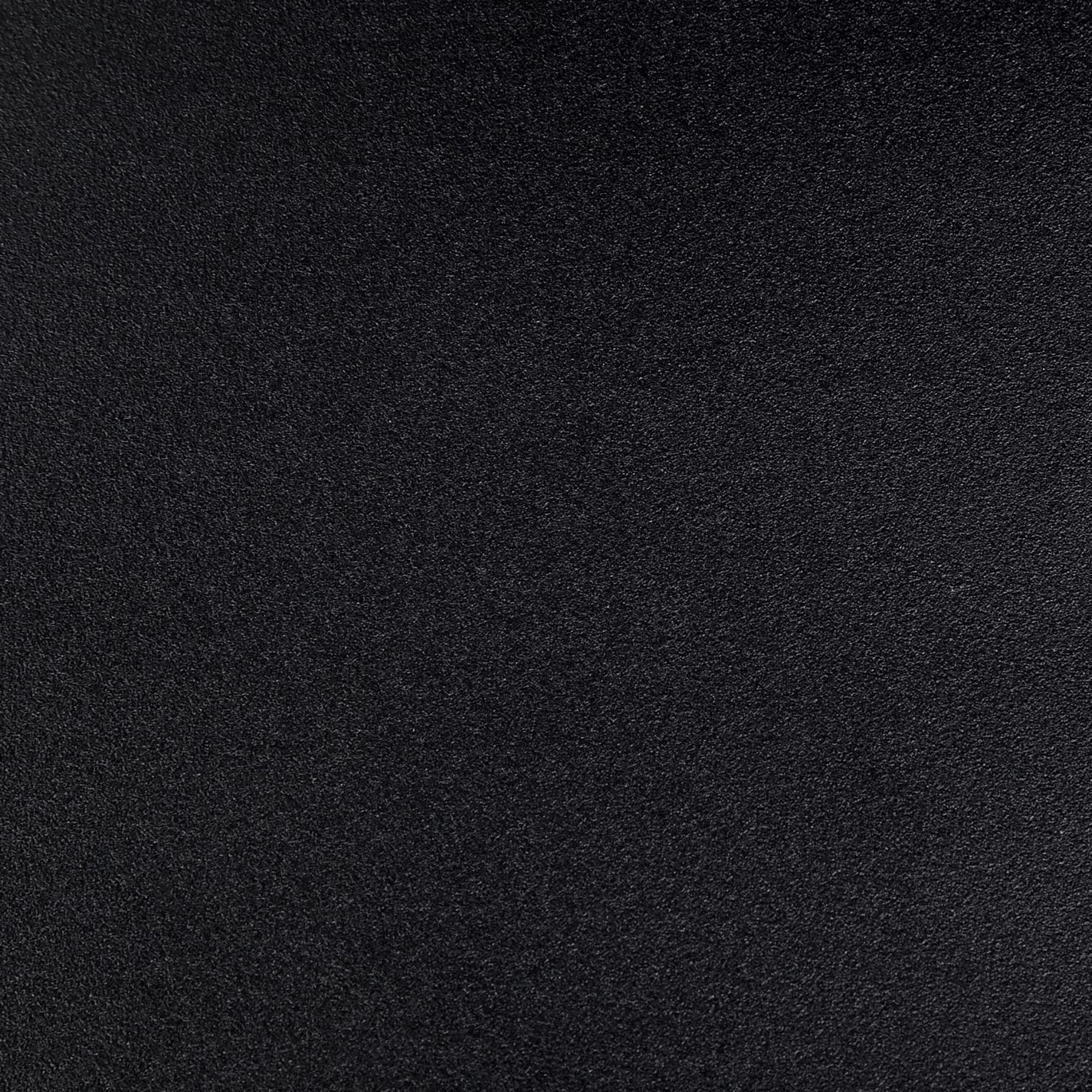 Nahaufnahme einer strukturierten, schwarzen Oberfläche. Die Textur wirkt körnig und leicht uneben.