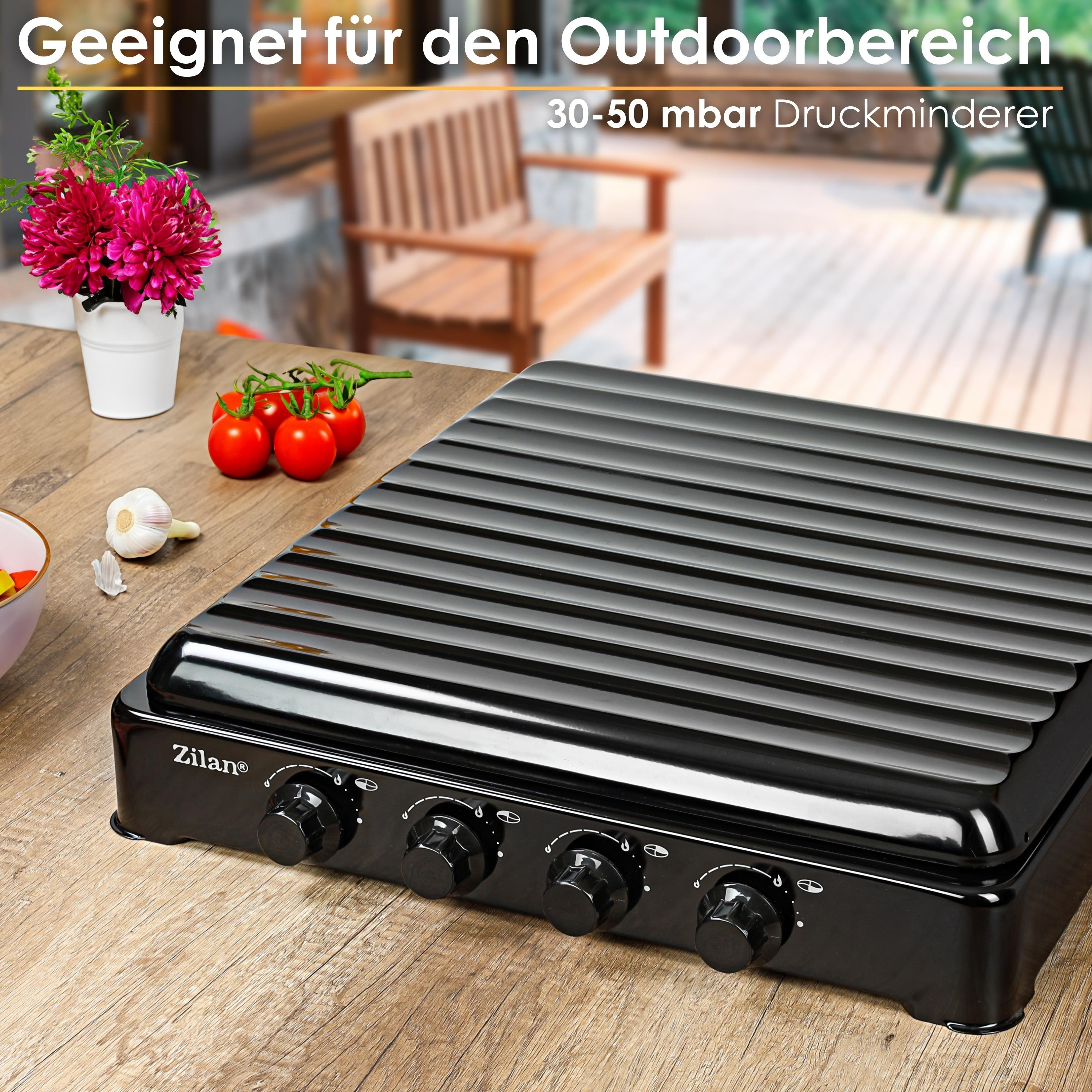 Czarny grill z pokrętłami na drewnianym stole. Pomidory, czosnek i kwiaty obok. Tło: patio.