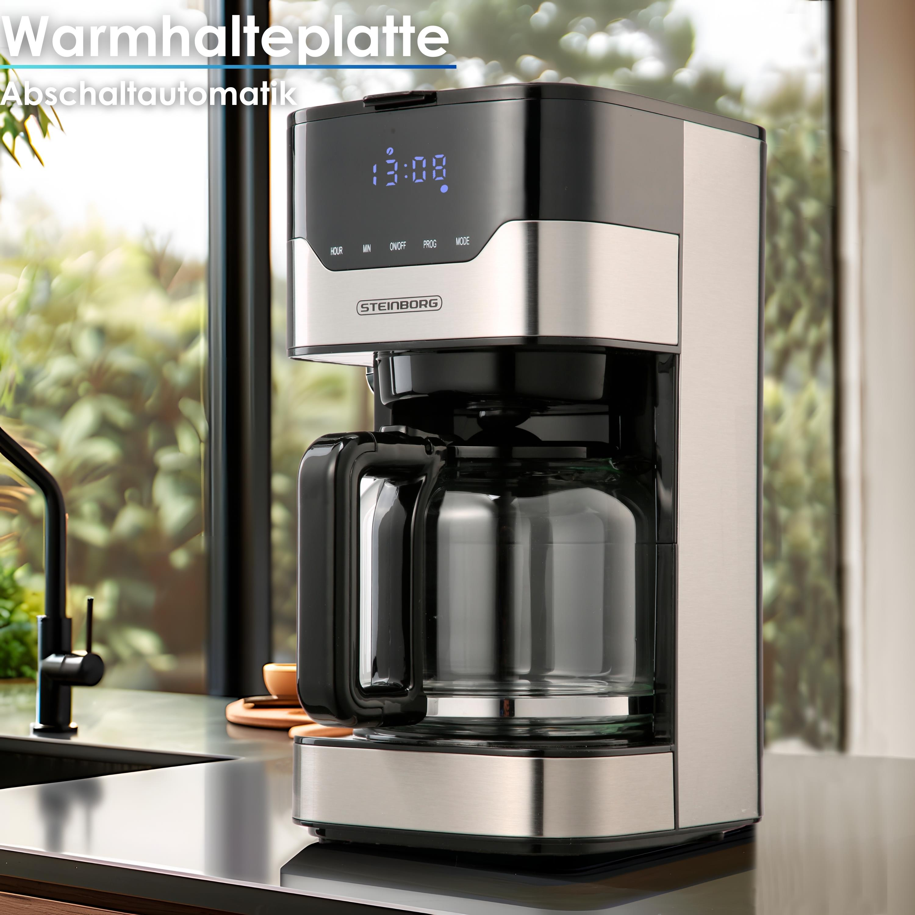 Eine Kaffeemaschine aus Edelstahl mit Glaskaraffe steht auf einer Theke. Die Uhrzeit 13:08 wird angezeigt.
