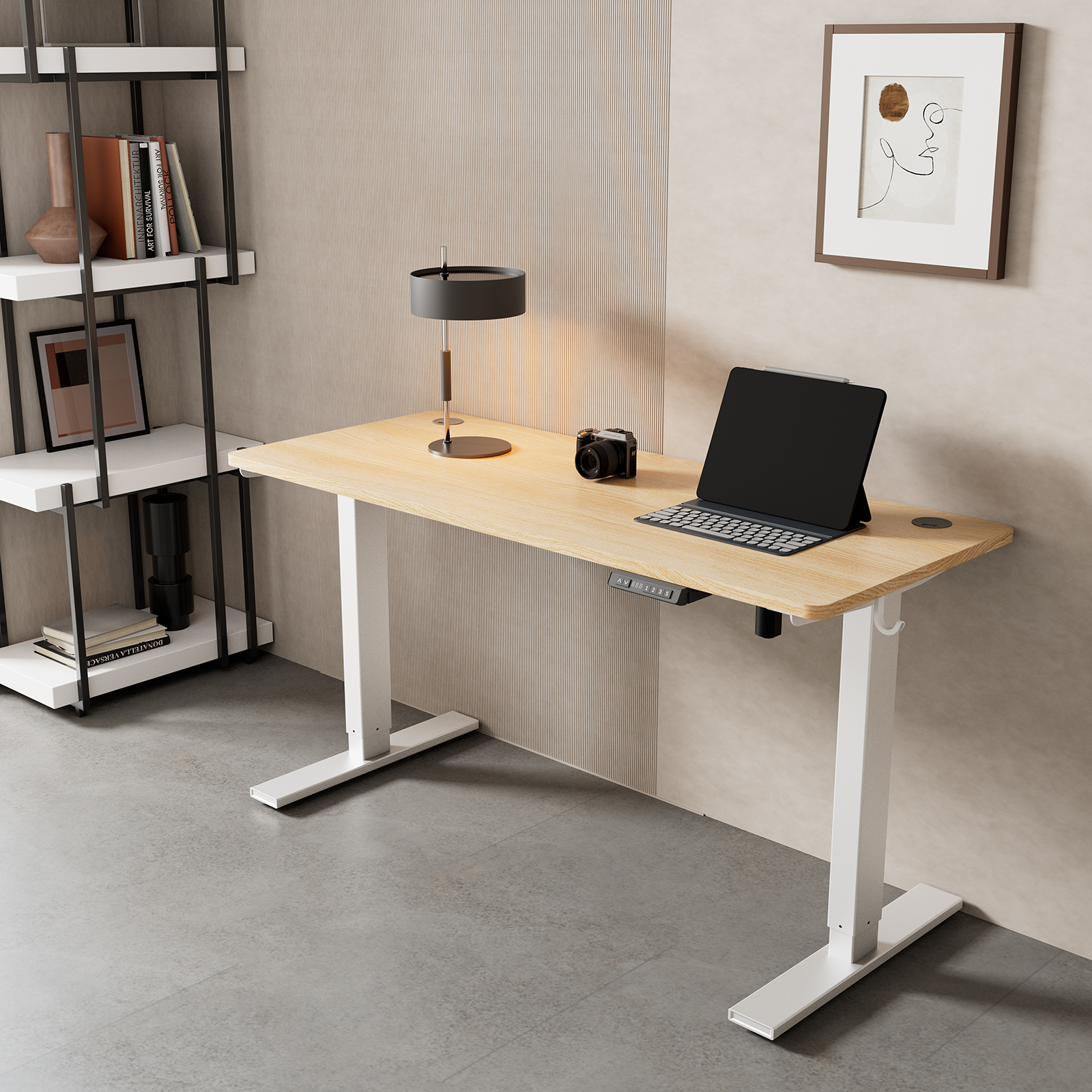 Ein moderner Schreibtisch mit Laptop, Kamera und Lampe vor einer gestreiften Wand. Links ein Regal und Kunstwerke.