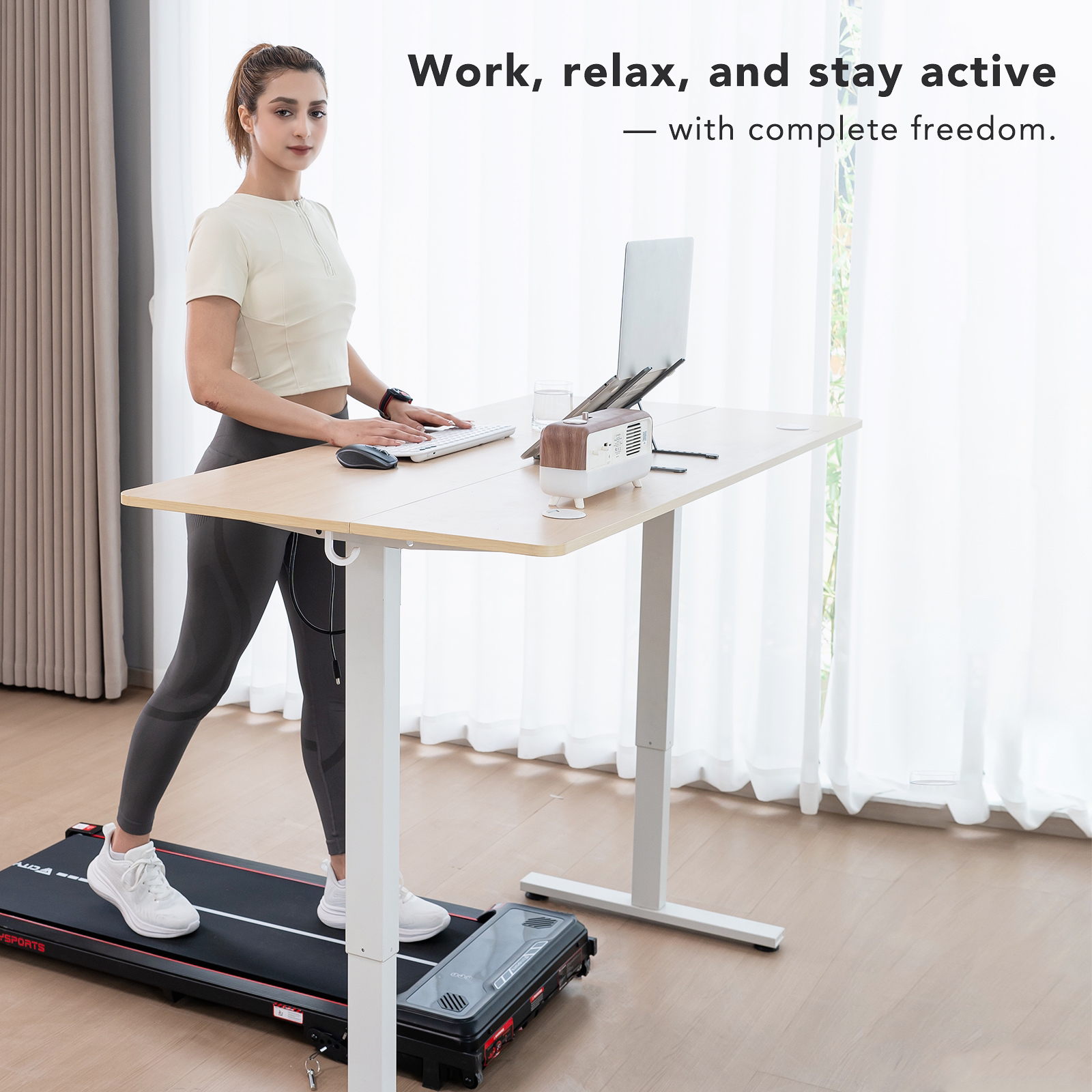 Frau, die an einem Laufband-Schreibtisch arbeitet. Sie tippt auf einer Tastatur, ein Laptop ist geöffnet. Der Hintergrund ist ein helles Fenster.