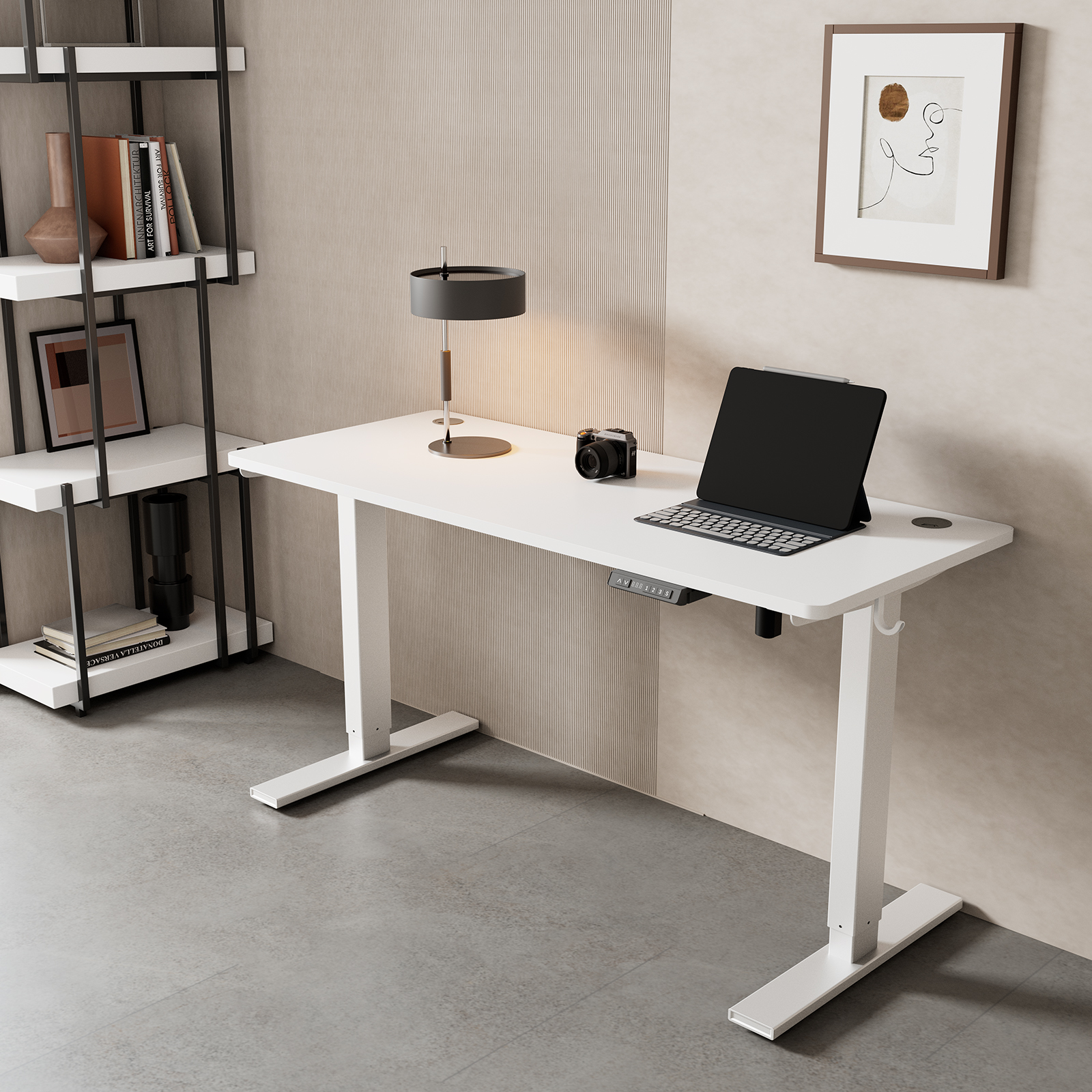 Ein weißer Schreibtisch mit Laptop, Kamera und Lampe. Bücherregal und Kunstwerk im Hintergrund. Die Wand ist beige.