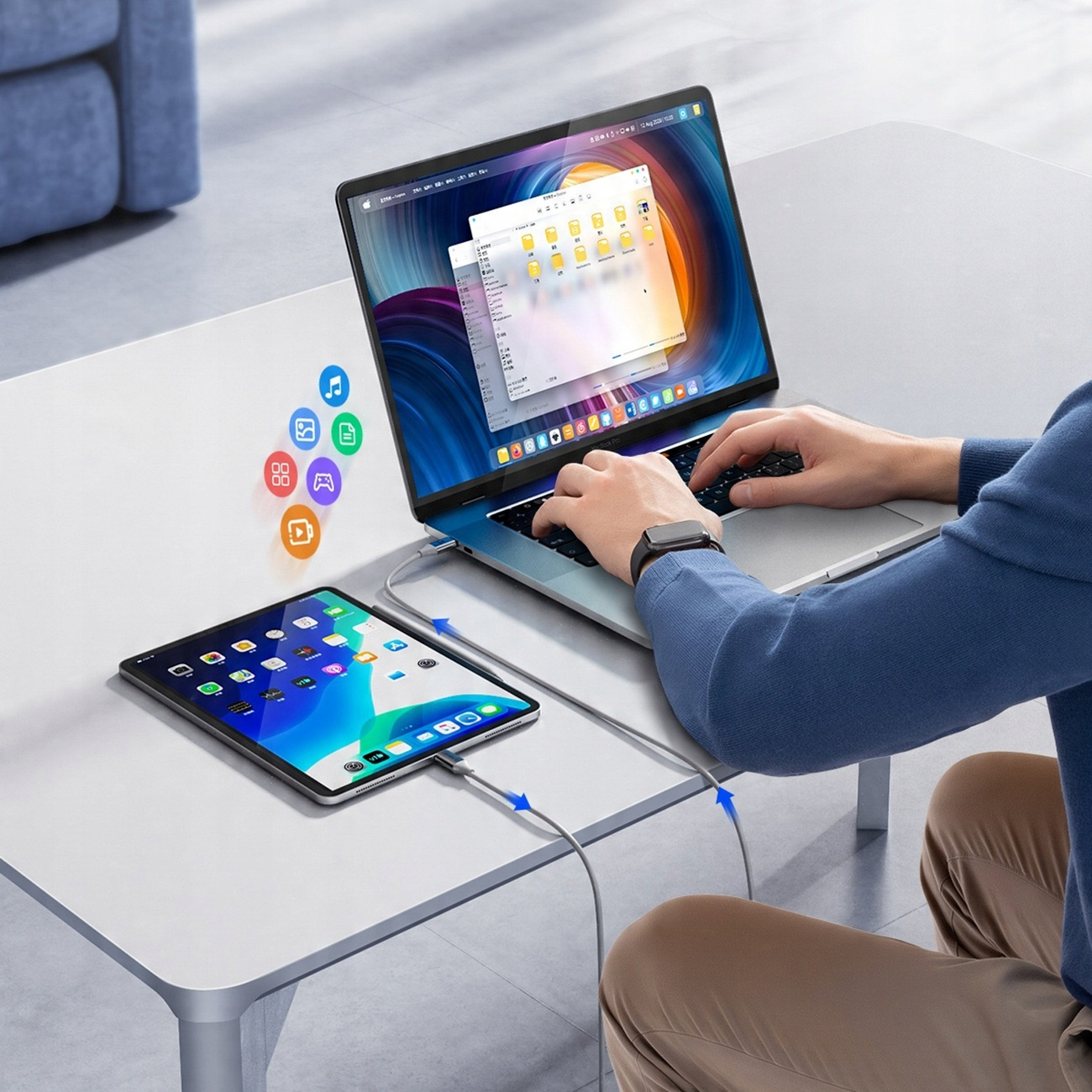 Laptop, Tablet und Kabel auf einem weißen Tisch verbunden. Eine Person benutzt den Laptop. Es gibt App-Symbole. Der Hintergrund ist ein blaues Sofa.