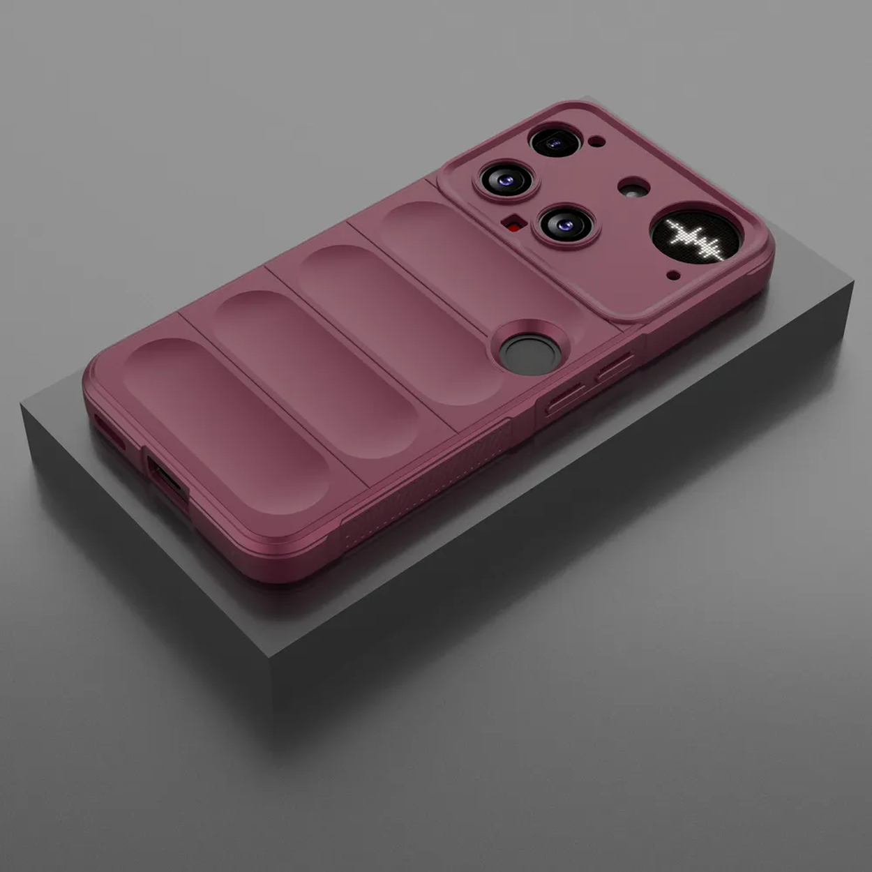 Een bordeauxrode telefoonhoes met camera-uitsparingen en een schuifdeksel ligt op een grijs blok tegen een grijze achtergrond.