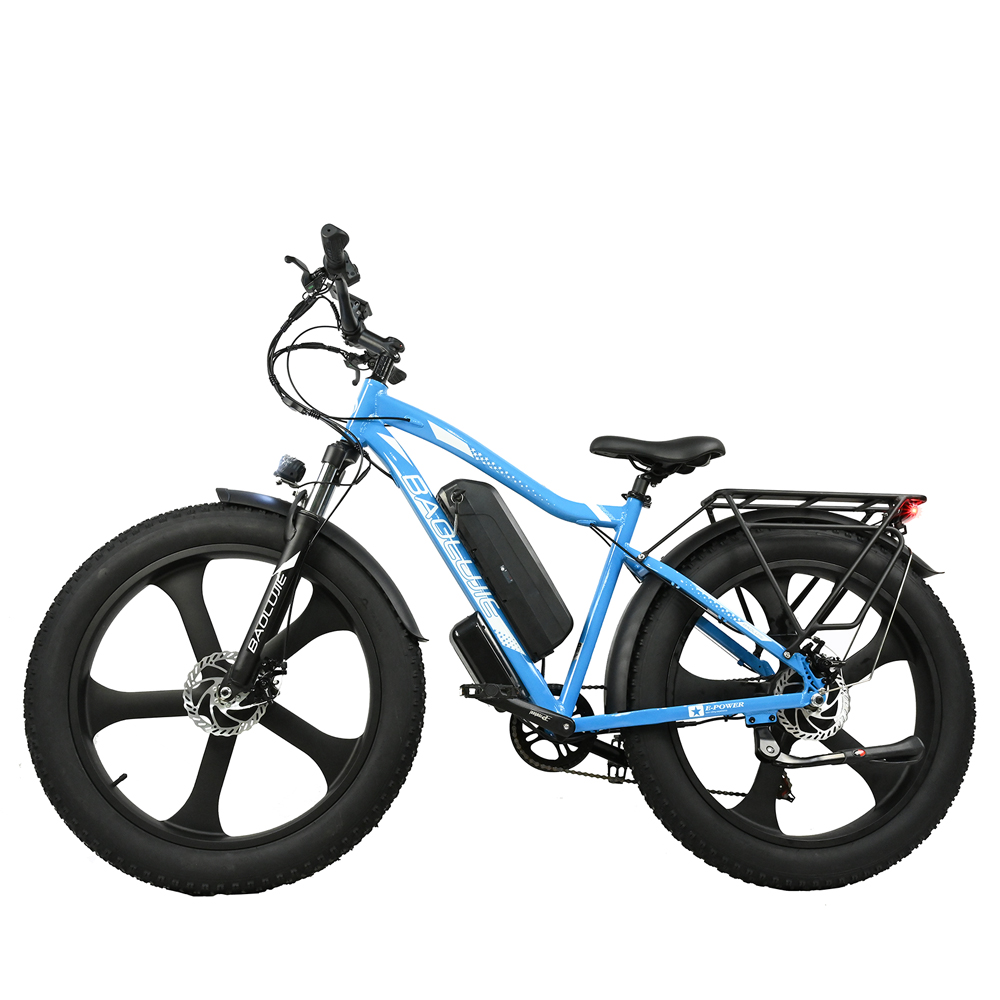 Se muestra una bicicleta eléctrica azul con neumáticos gruesos. Tiene una batería negra, un portaequipajes y un fondo blanco.