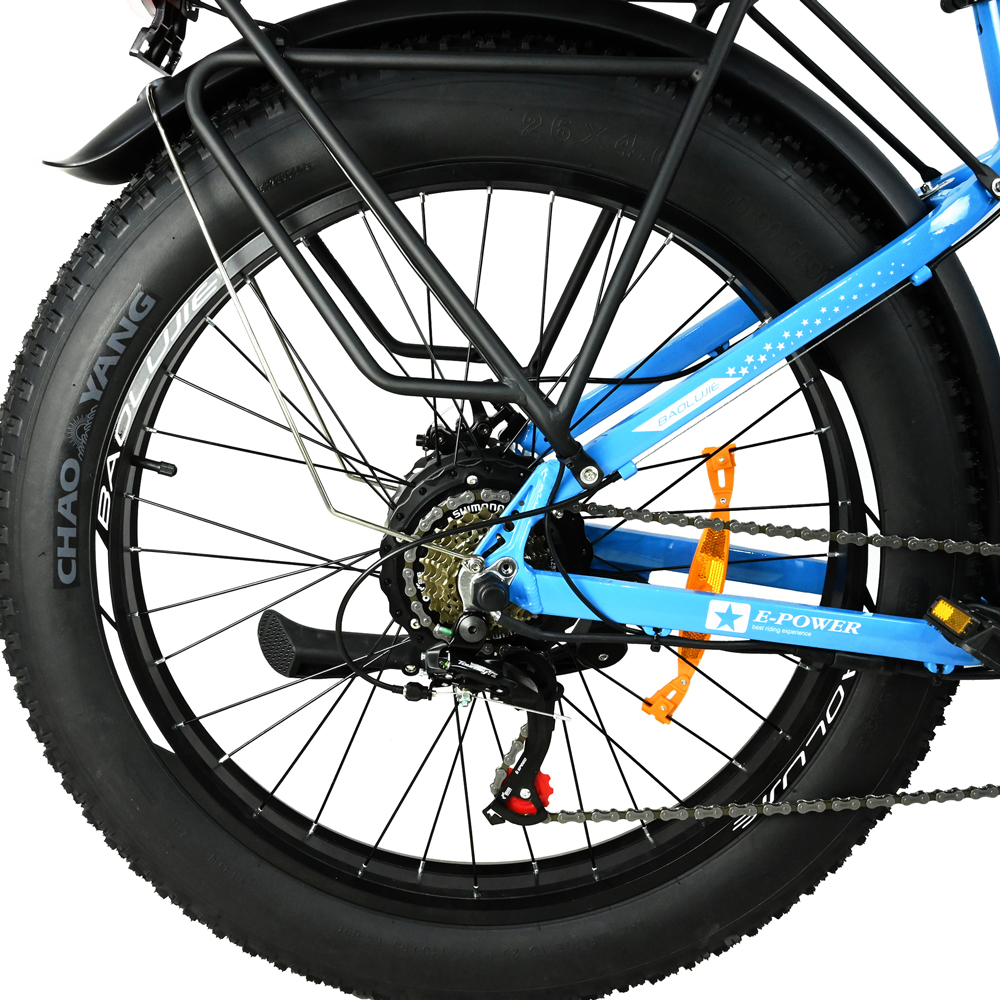 Primer plano de la rueda trasera de una bicicleta eléctrica azul. El neumático es negro, el cuadro azul. La bici tiene un sistema de engranajes y una cadena.