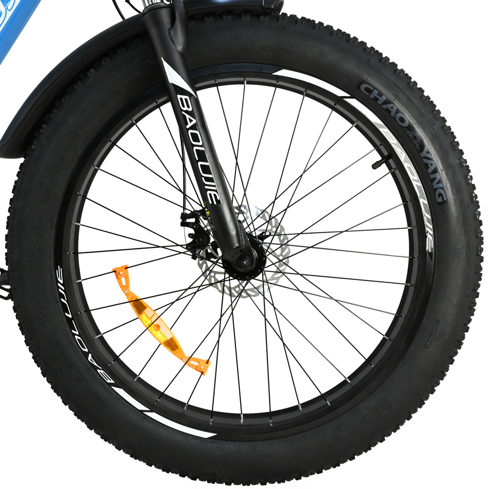 Primer plano de una rueda de bicicleta. Neumático, radios y llanta negros. La horquilla dice BAOLUIE. Lleva un reflector naranja.