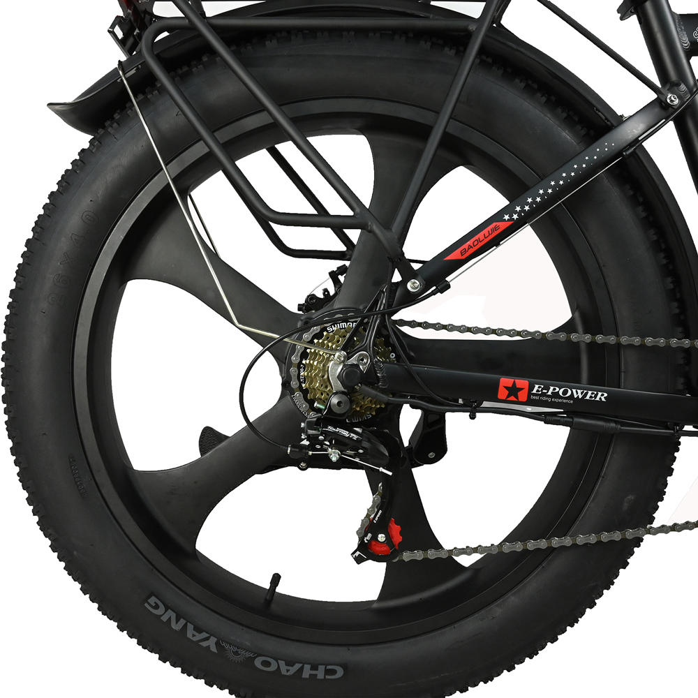 Primer plano de una rueda negra de bicicleta eléctrica. El grueso neumático tiene 'CHAO YANG'. La rueda tiene cinco radios y una cadena.