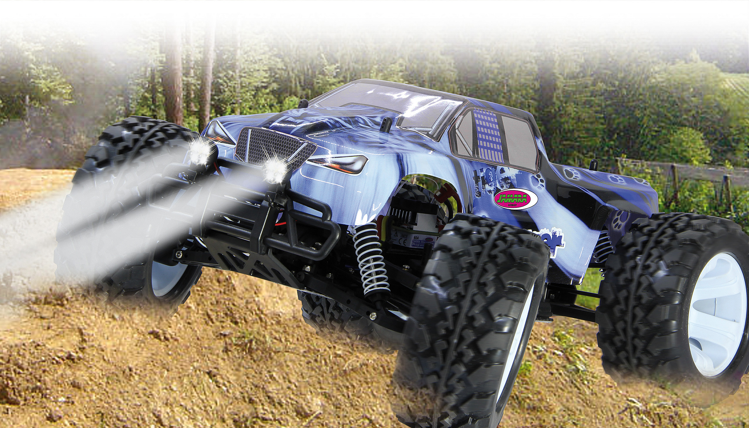 Ein blau-schwarzer Monstertruck springt über Schmutz. Der Hintergrund umfasst Bäume und einen Zaun. Rauch geht von Reifen aus.