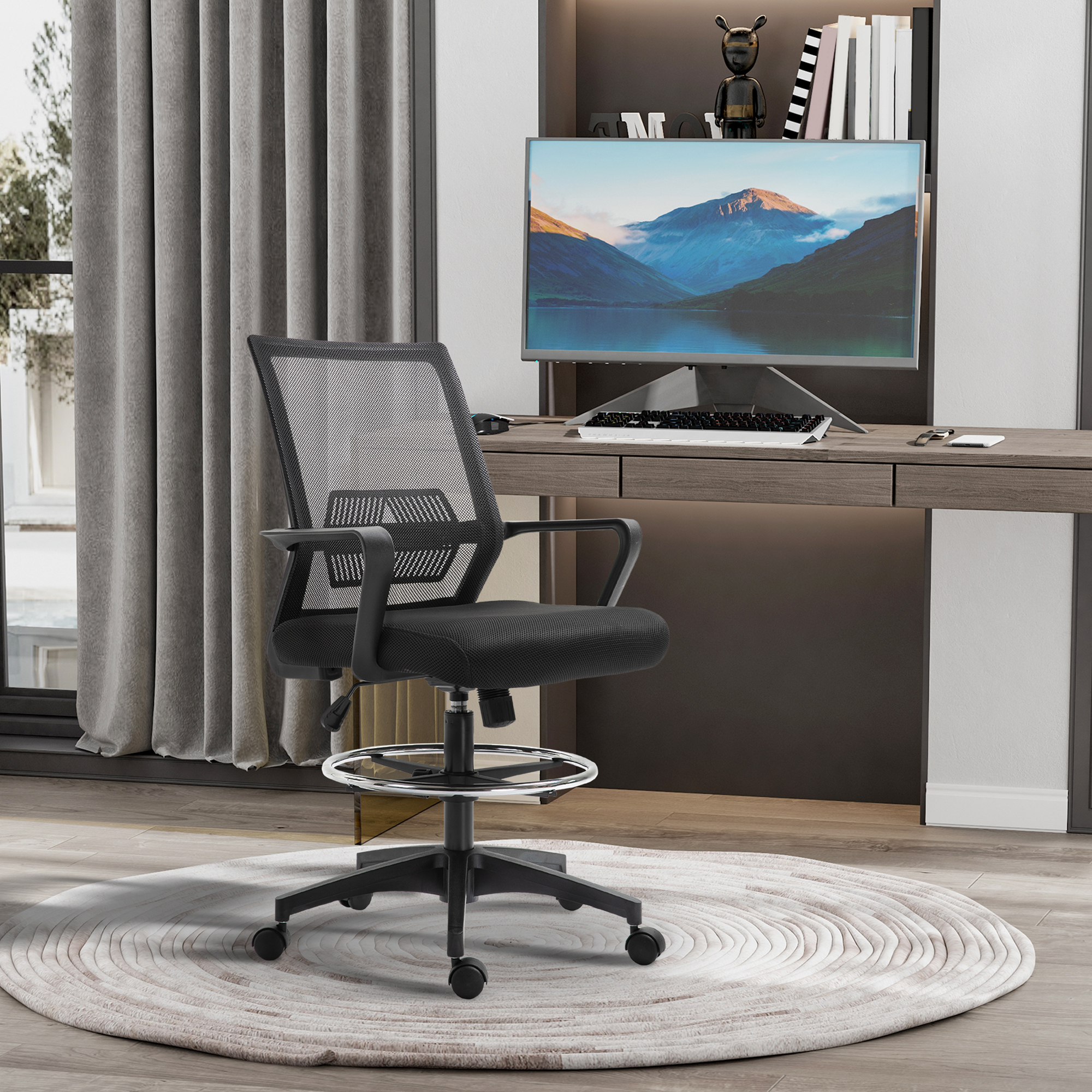 Una sedia da ufficio in rete nera è davanti a una scrivania con un monitor che mostra una scena di montagna. C'è un tappeto sotto.