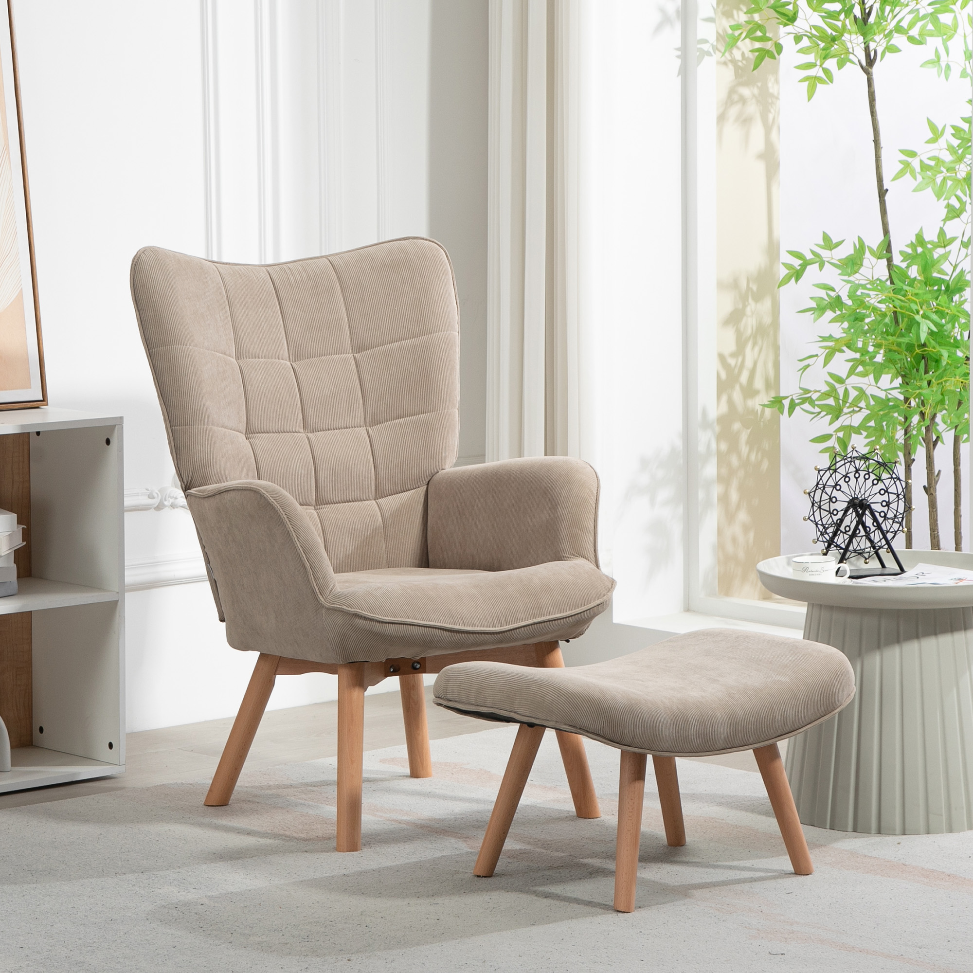 Poltrona beige con pouf su gambe in legno. Un tavolino con una ruota decorativa e una pianta sono vicini, vicino a una finestra.