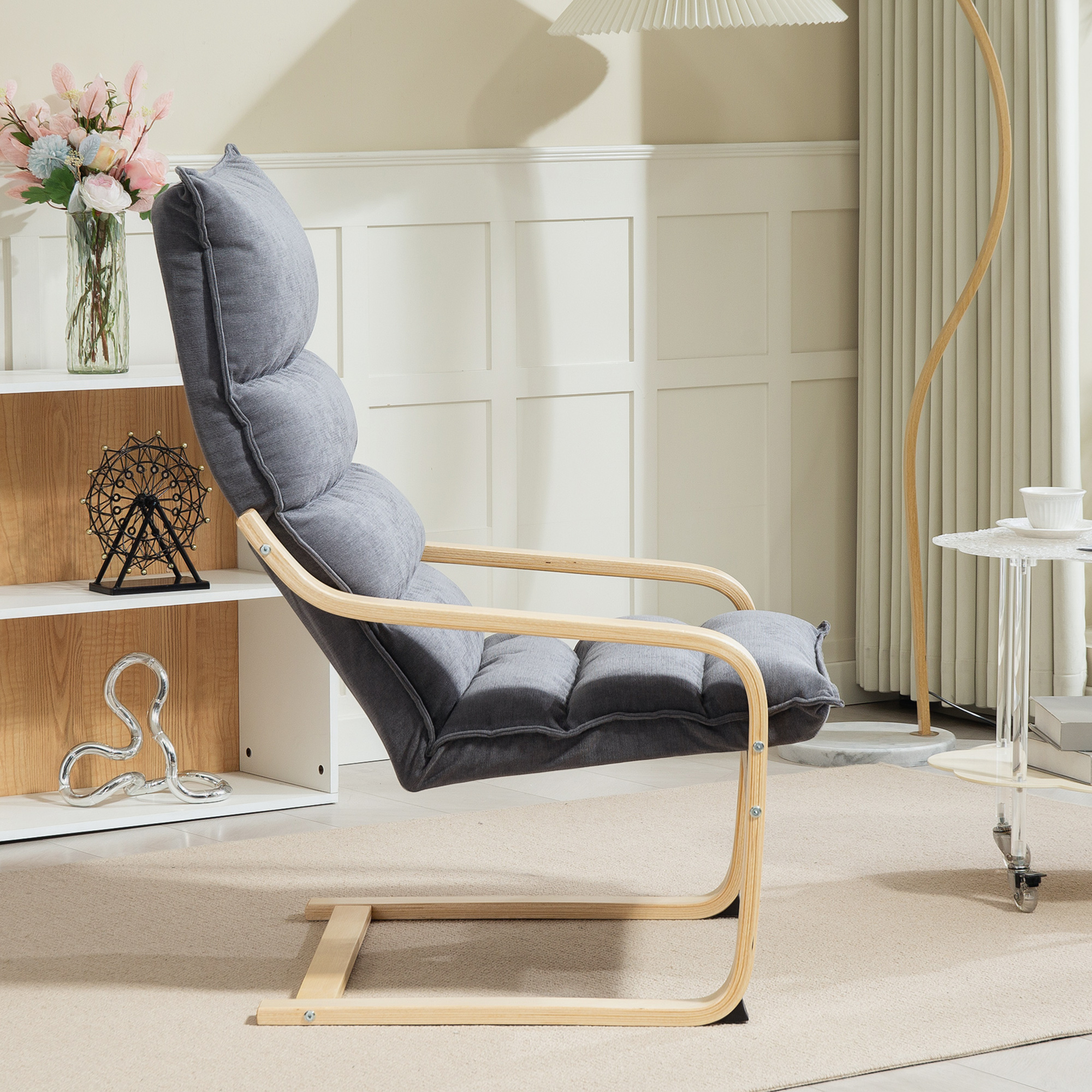 Una poltrona grigia con struttura in legno su un tappeto beige. A sinistra una mensola con decorazioni. Luce soffusa a destra.
