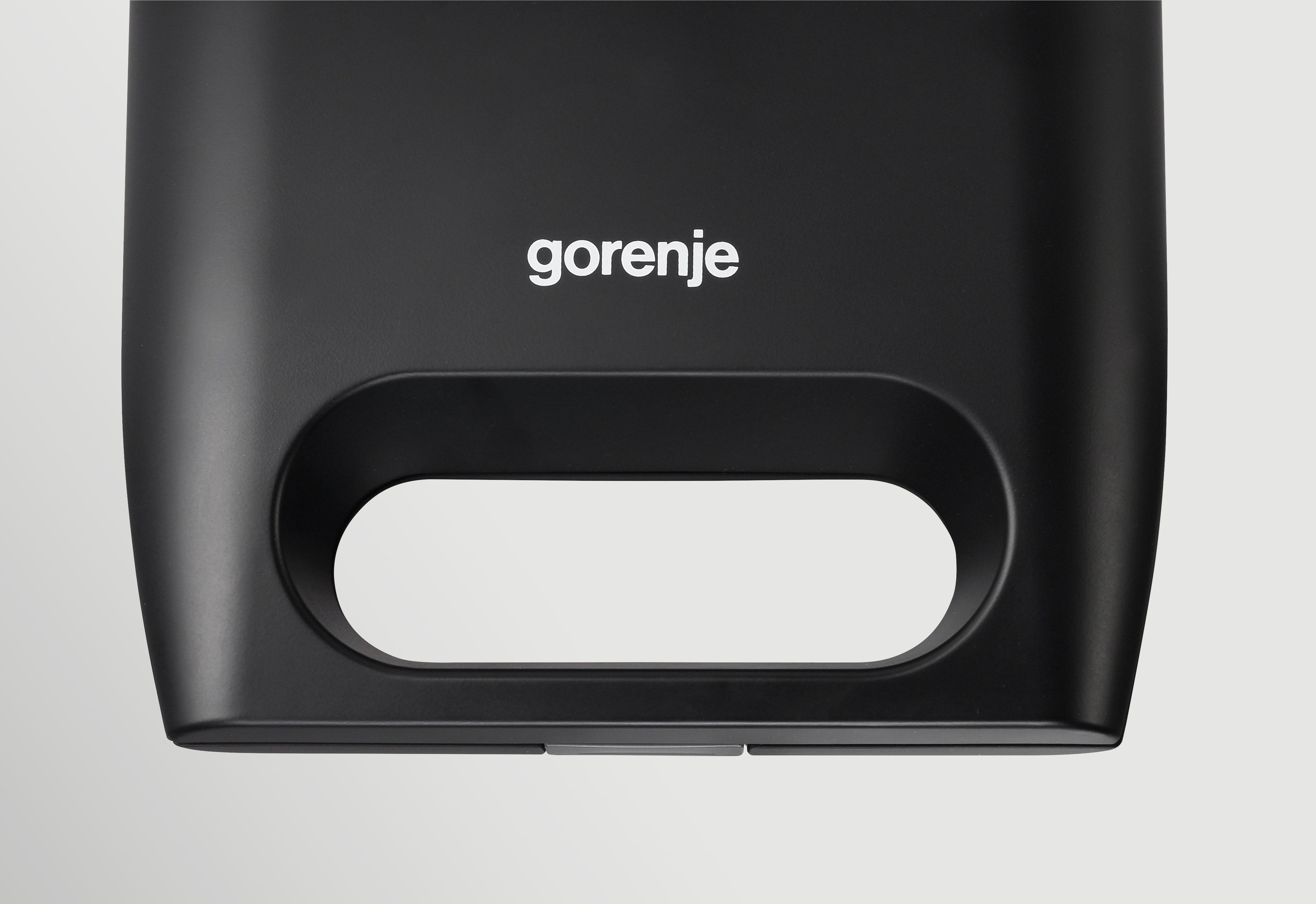 Czarne urządzenie z owalnym uchwytem na białym tle. Marka 'gorenje' u góry.