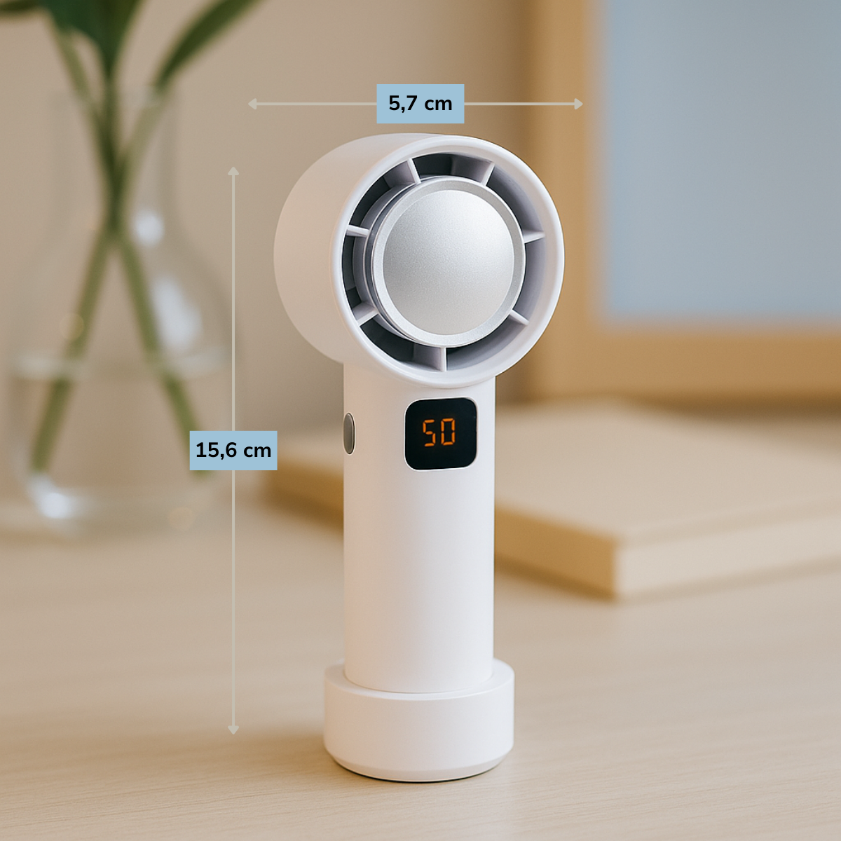 Un ventilateur portable blanc avec un affichage numérique indiquant '50' est posé sur une surface en bois. Un vase en verre avec des plantes est en arrière-plan.