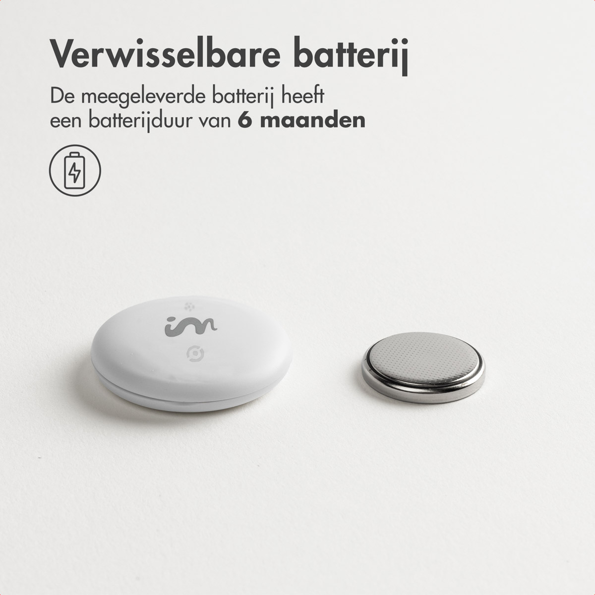 A white, oval-shaped device and a silver button battery are on a white surface. Text at top says 'Replaceable battery'.