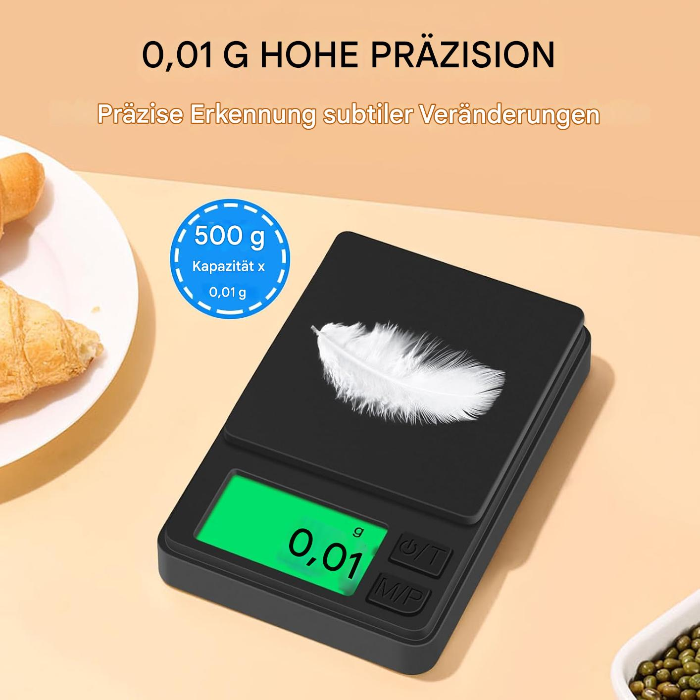 Eine schwarze Digitalwaage mit einer Feder. Die Anzeige zeigt 0,01 g. Text oben sagt Präzision und 500 g Kapazität.