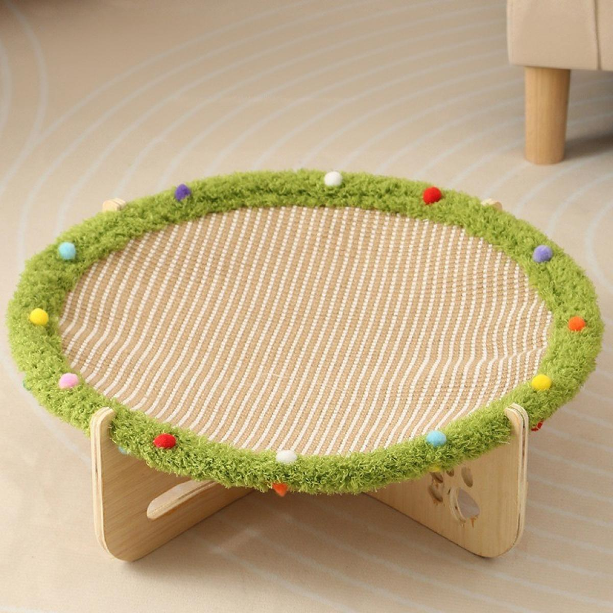 Katzenbett mit grünem Rand und bunten Pompons, beigefarbener gestreifter Mitte. Holzsockel. Beiger Boden, Teilsofa im Hintergrund.