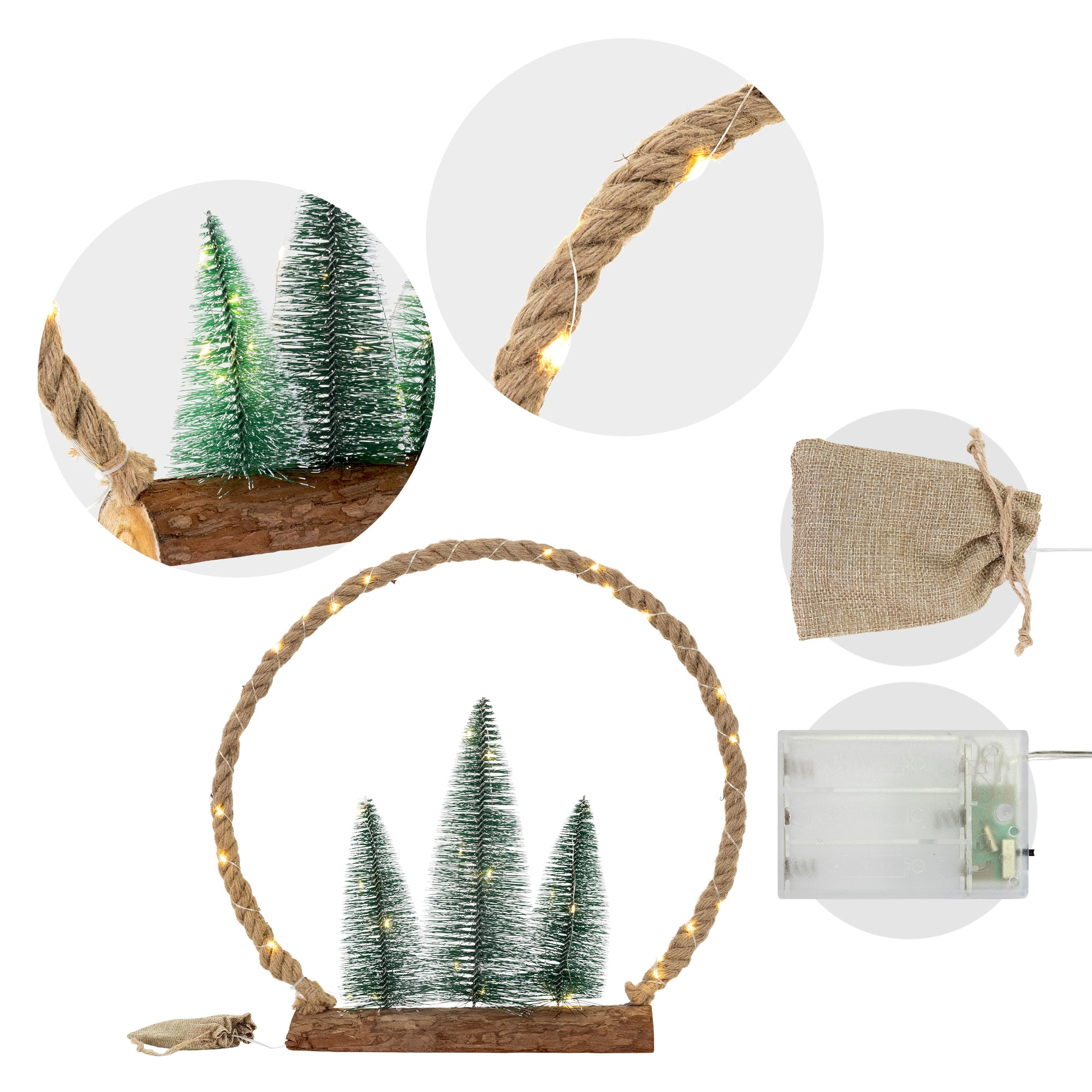 Eine Weihnachtsdekoration. Drei kleine grüne Bäume auf Holzsockel, umgeben von einem Seilkreis mit Lichtern. Ein kleiner Beutel und ein Akkupack.