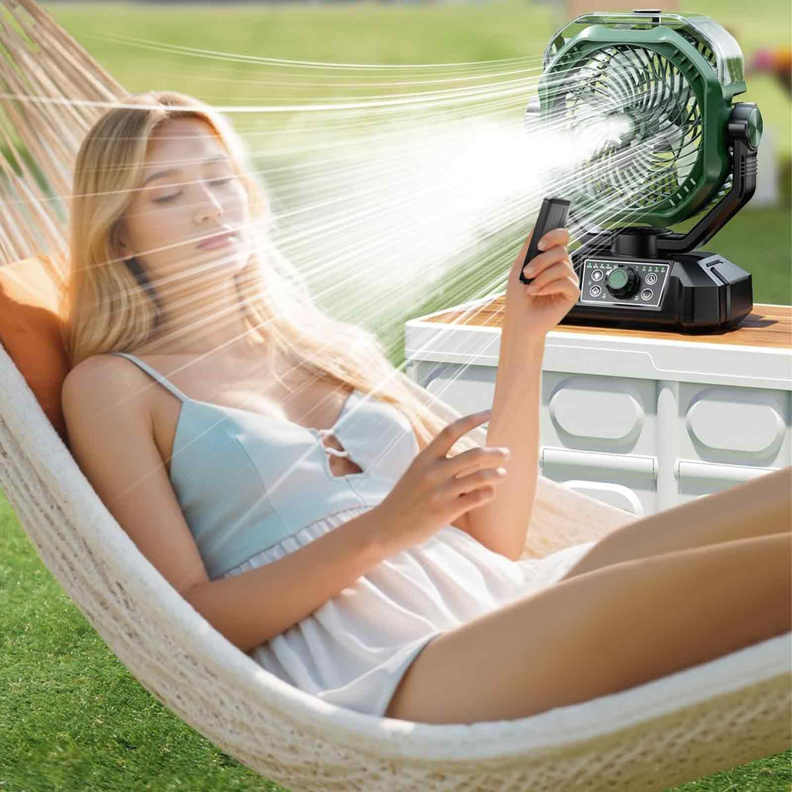 Frau entspannt sich in der Hängematte mit Ventilator und Fernbedienung. Grüner Ventilator auf dem Tisch, helles Sonnenlicht.