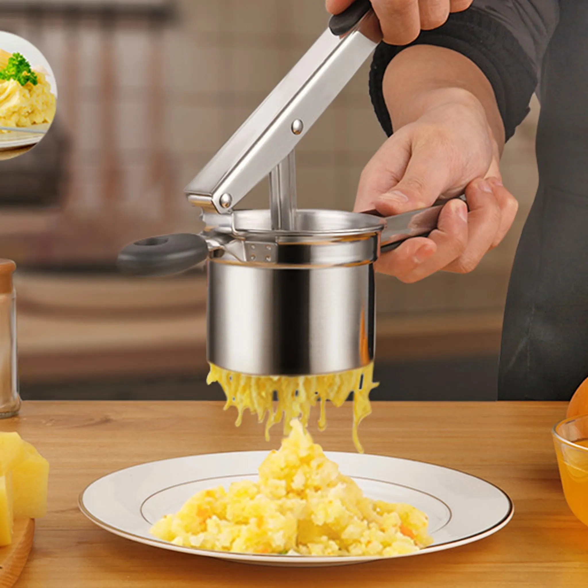 Eine Person, die Kartoffeln mit einem Kartoffelstampfer aus Edelstahl presst. Kartoffelpüree fällt auf einen Teller. Im Hintergrund befindet sich eine kleine Schüssel mit Essen.