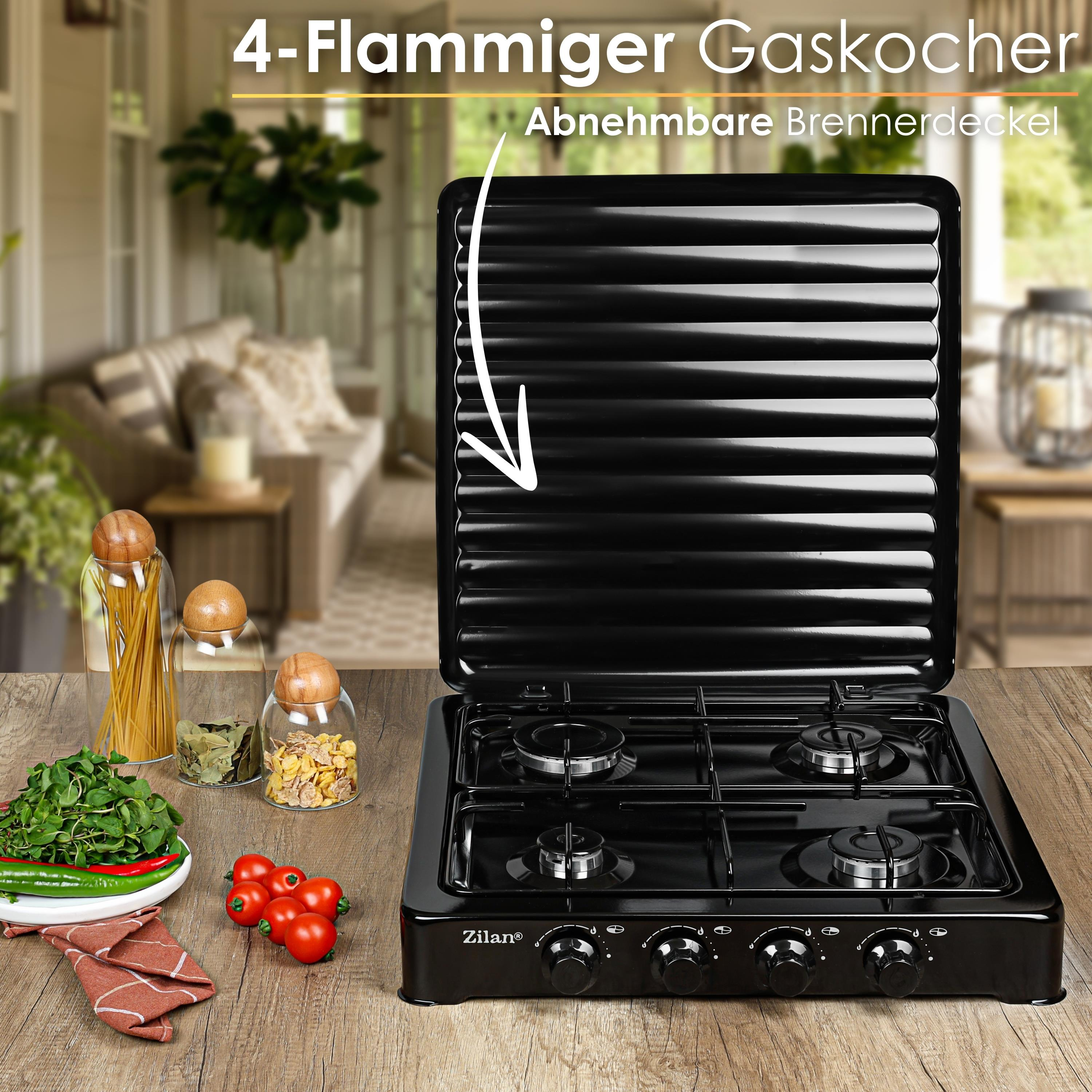 Czarna 4-palnikowa kuchenka gazowa z otwartą pokrywą stoi na drewnianym stole. Warzywa, przyprawy i słoiki po lewej.
