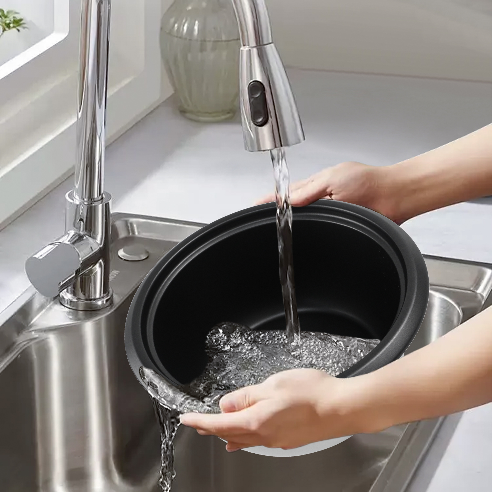Eine Person wäscht einen schwarzen Topf unter einem silbernen Wasserhahn in einem Edelstahlbecken. Wasser fließt in den Topf.