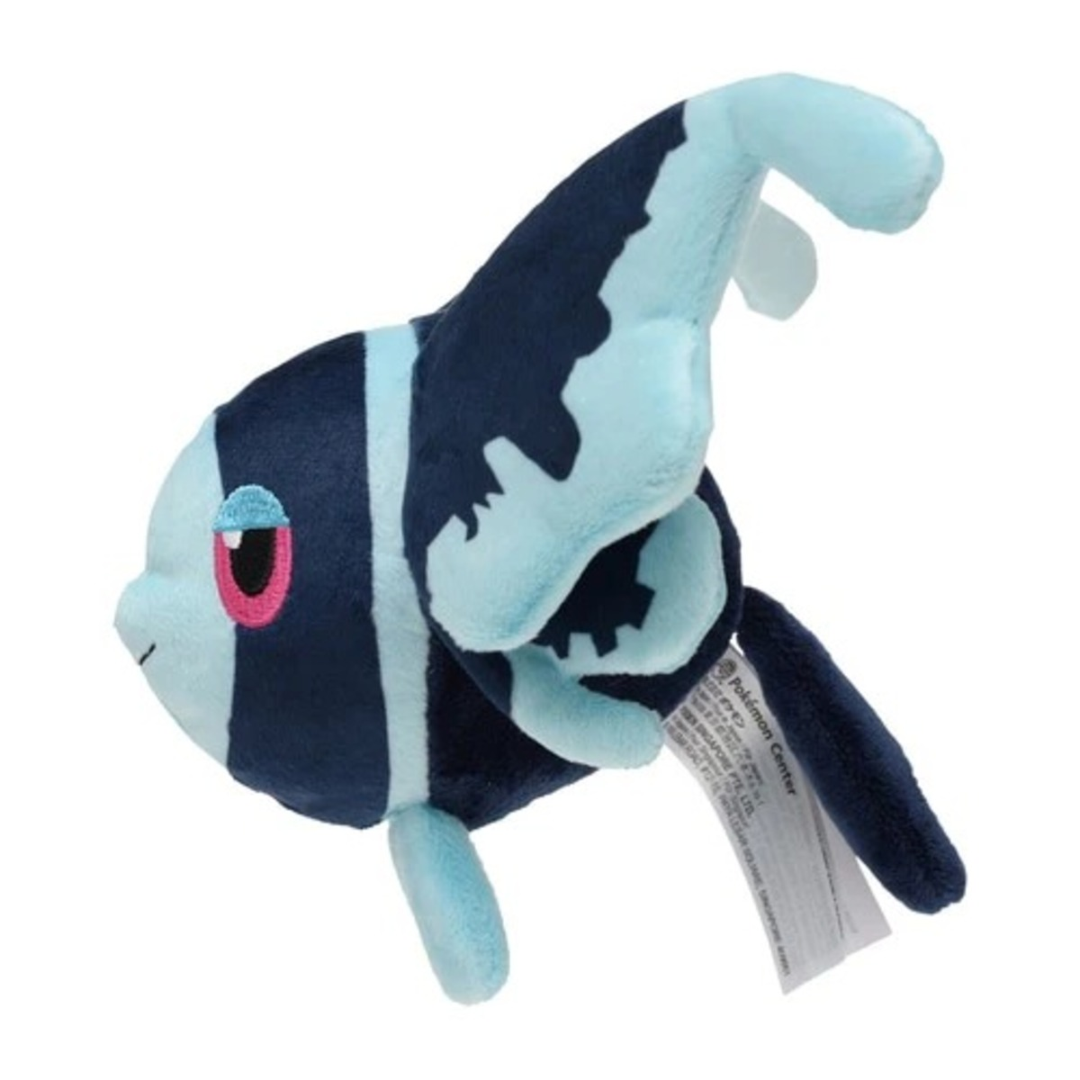 Ein Plüschtier in Form eines Fisches. Es hat blaue und marineblaue Streifen, ein rosa Auge und ein weißes Etikett. Der Hintergrund ist weiß.