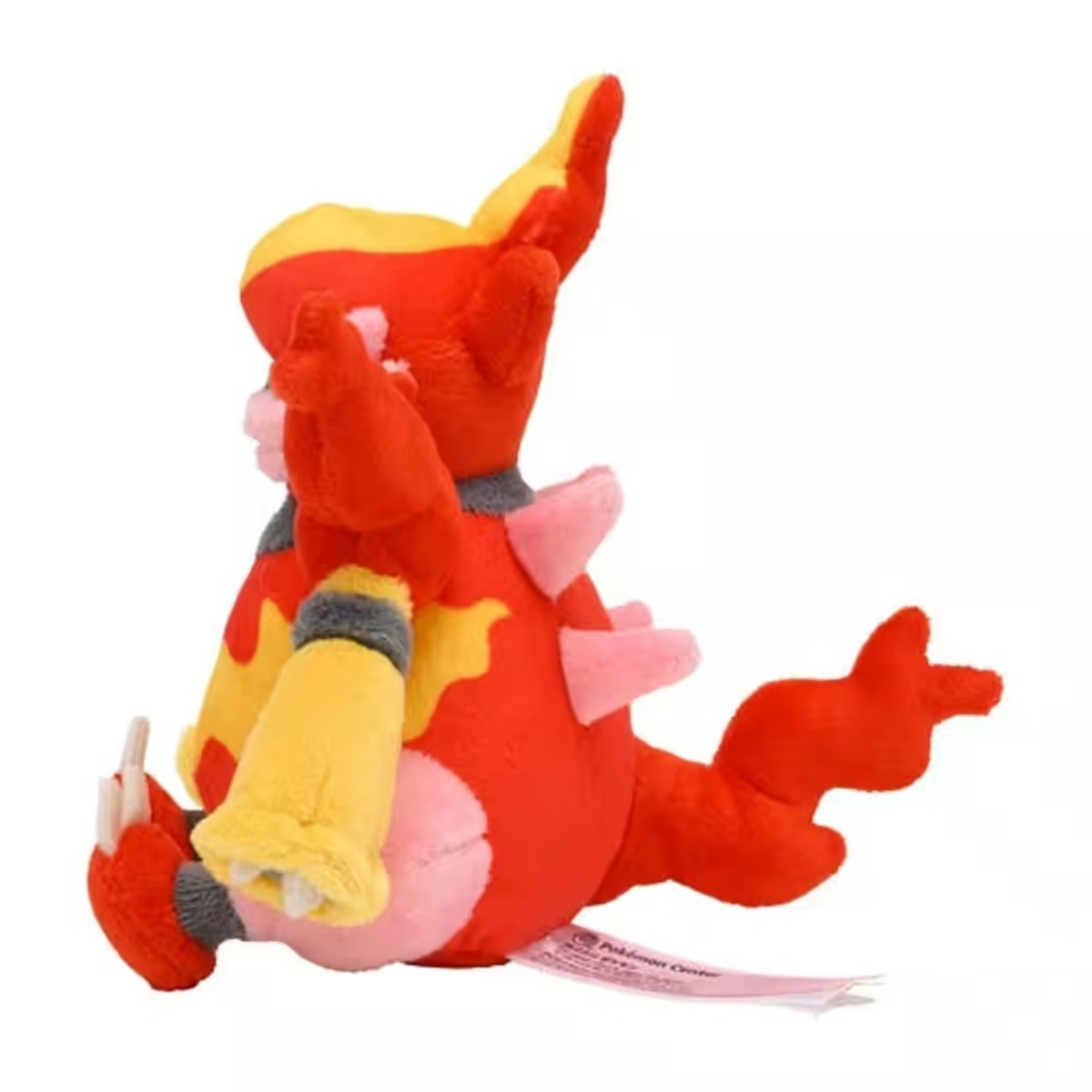 Ein Plüschtier einer rot-gelben Kreatur mit rosa Akzenten. Es hat einen Schwanz und ein Etikett mit der Aufschrift 'Pokemon Center'.
