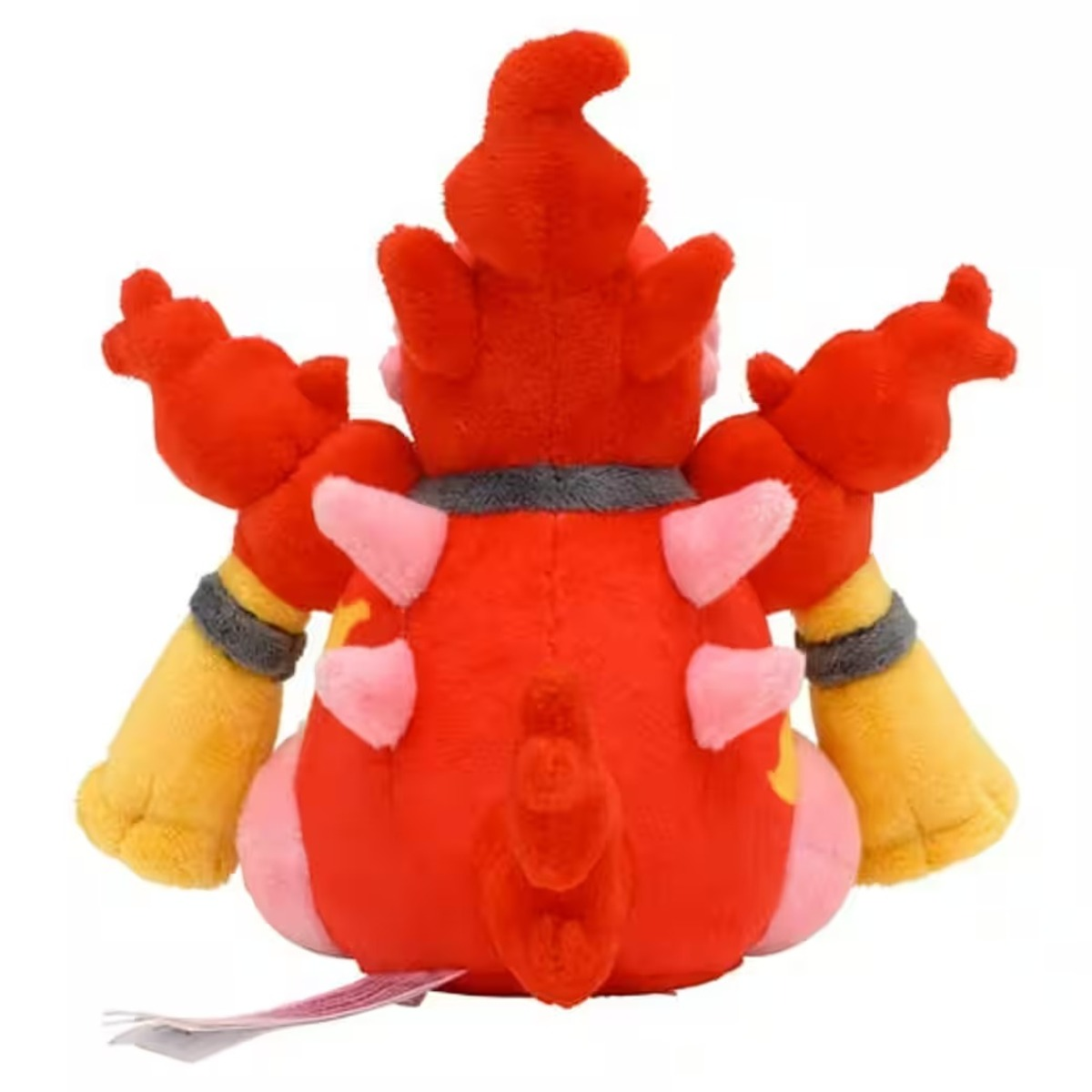 Ein Plüschtier, rot und gelb mit rosa Akzenten, wird von hinten gezeigt. Es hat einen Schwanz und zwei Arme. Unten ist ein Etikett zu sehen.
