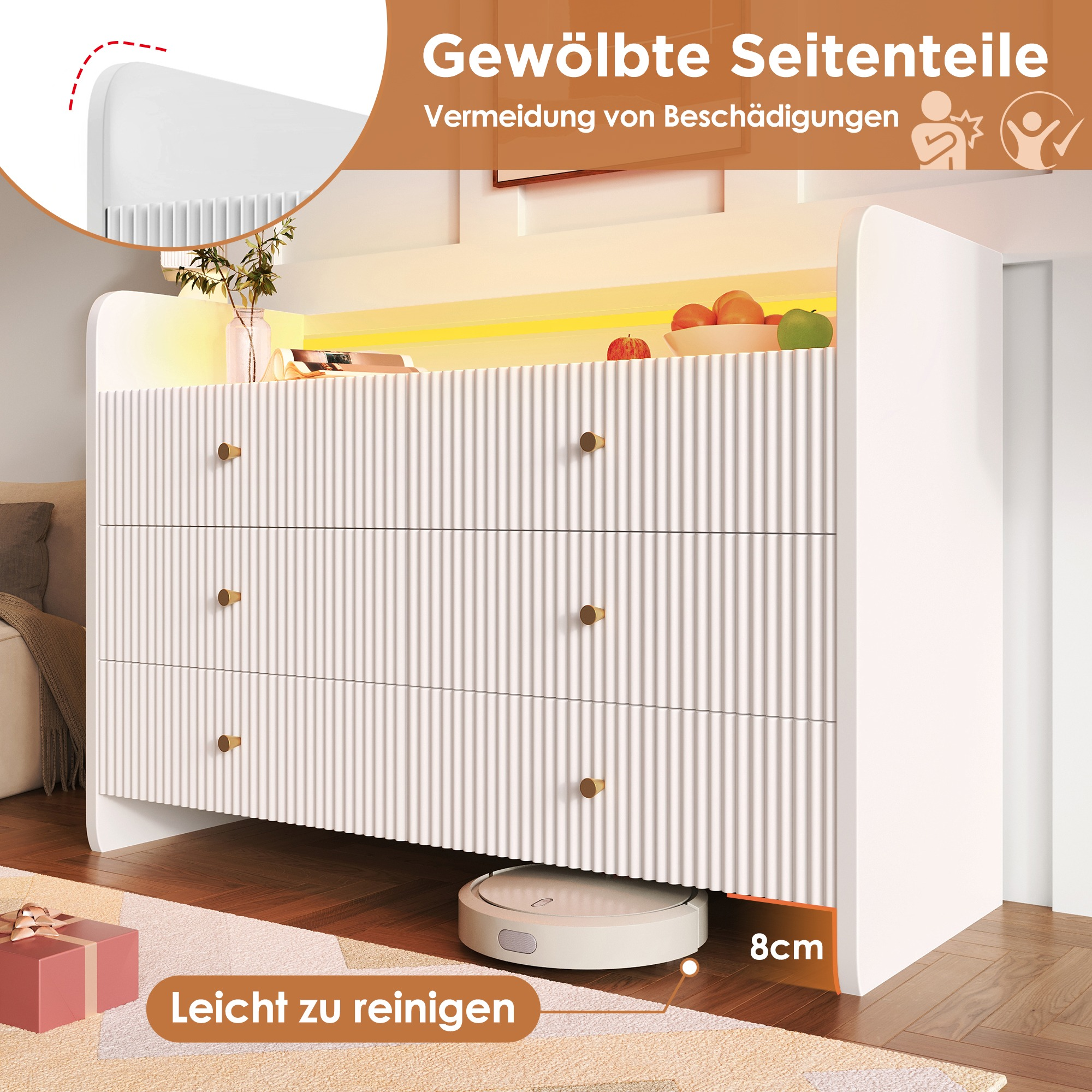 Weiße Kommode mit drei Schubladen. Früchte und eine Pflanze stehen oben. Ein Roboter-Staubsauger ist darunter. Es ist leicht zu reinigen.