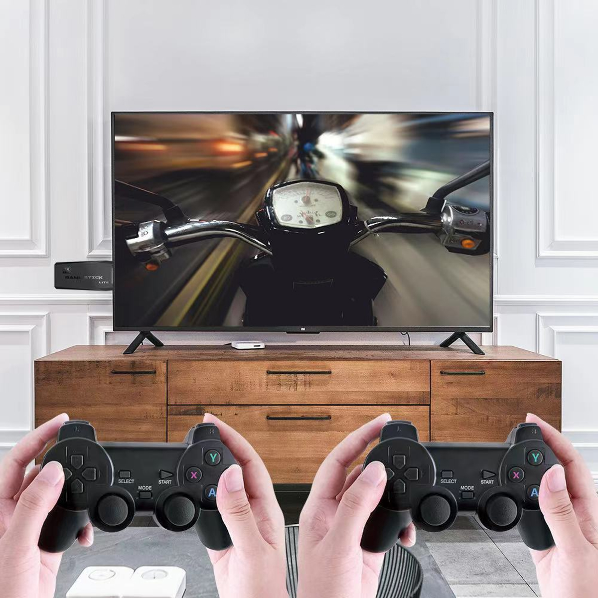 Hände halten Gamecontroller und spielen ein Motorradrennspiel im Fernsehen. Der Fernseher steht auf einem Holzschrank.