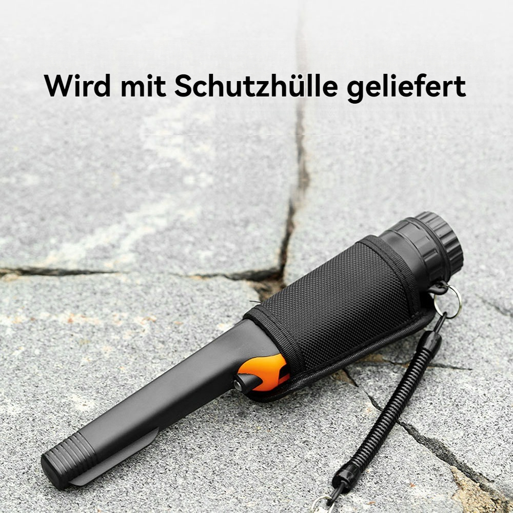 Ein schwarzer Metalldetektor in einer schwarzen Hülle mit einem orangefarbenen Element auf einer grauen Steinoberfläche. Text oben: Wird mit Schutzhülle geliefert.