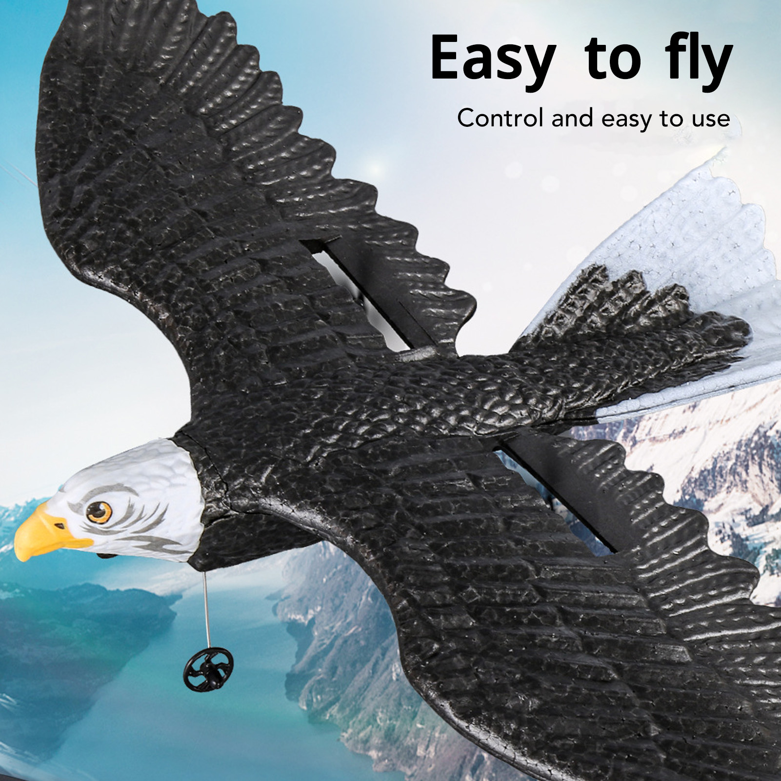 Ein schwarz-weißes Adler-Spielzeug fliegt. Es hat einen gelben Schnabel. Der Hintergrund zeigt einen Berg und blauen Himmel.