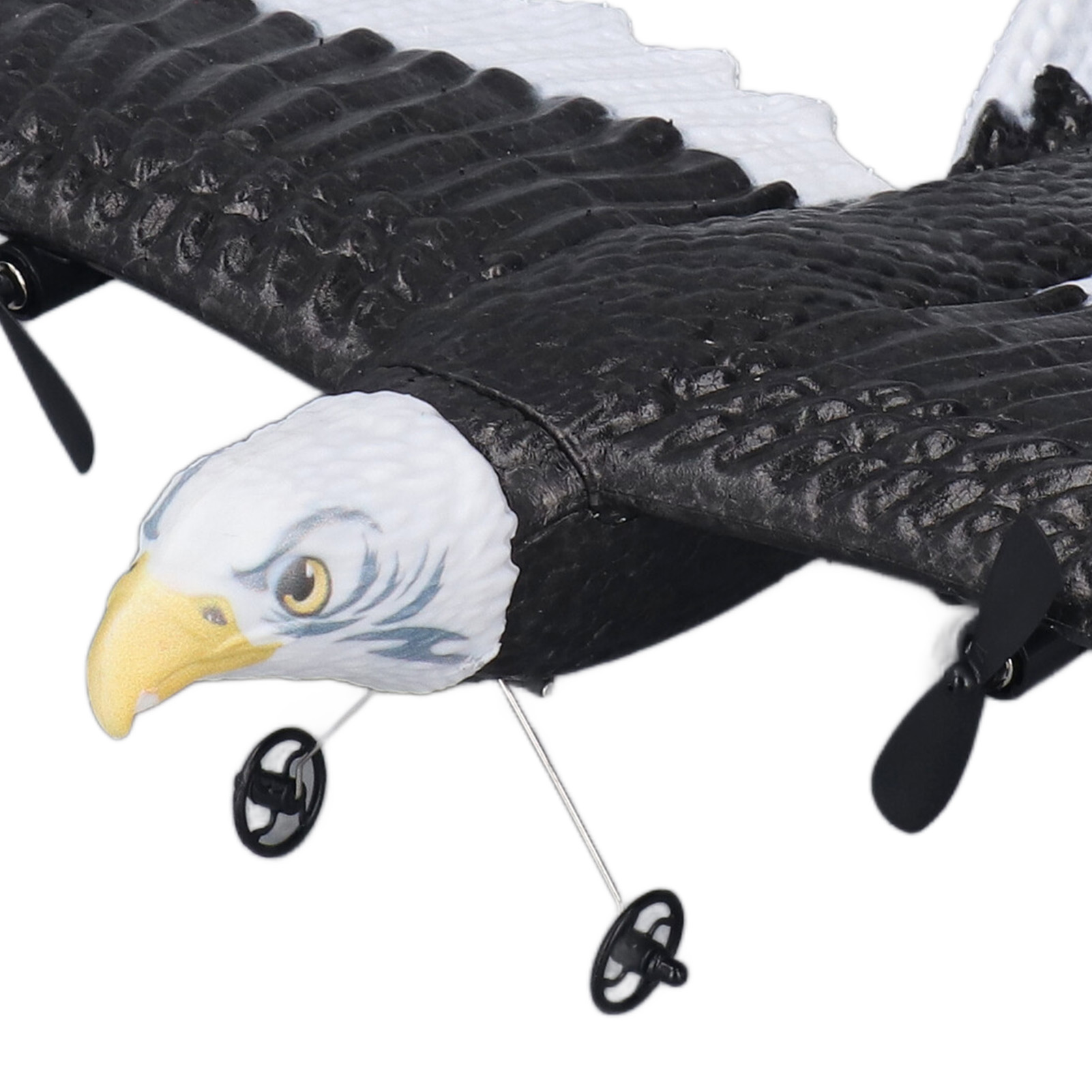 Ein Modell-Adler-Segelflugzeug mit schwarz-weißen Flügeln, einem gelben Schnabel und kleinen schwarzen Propellern und Rädern auf weißem Grund.
