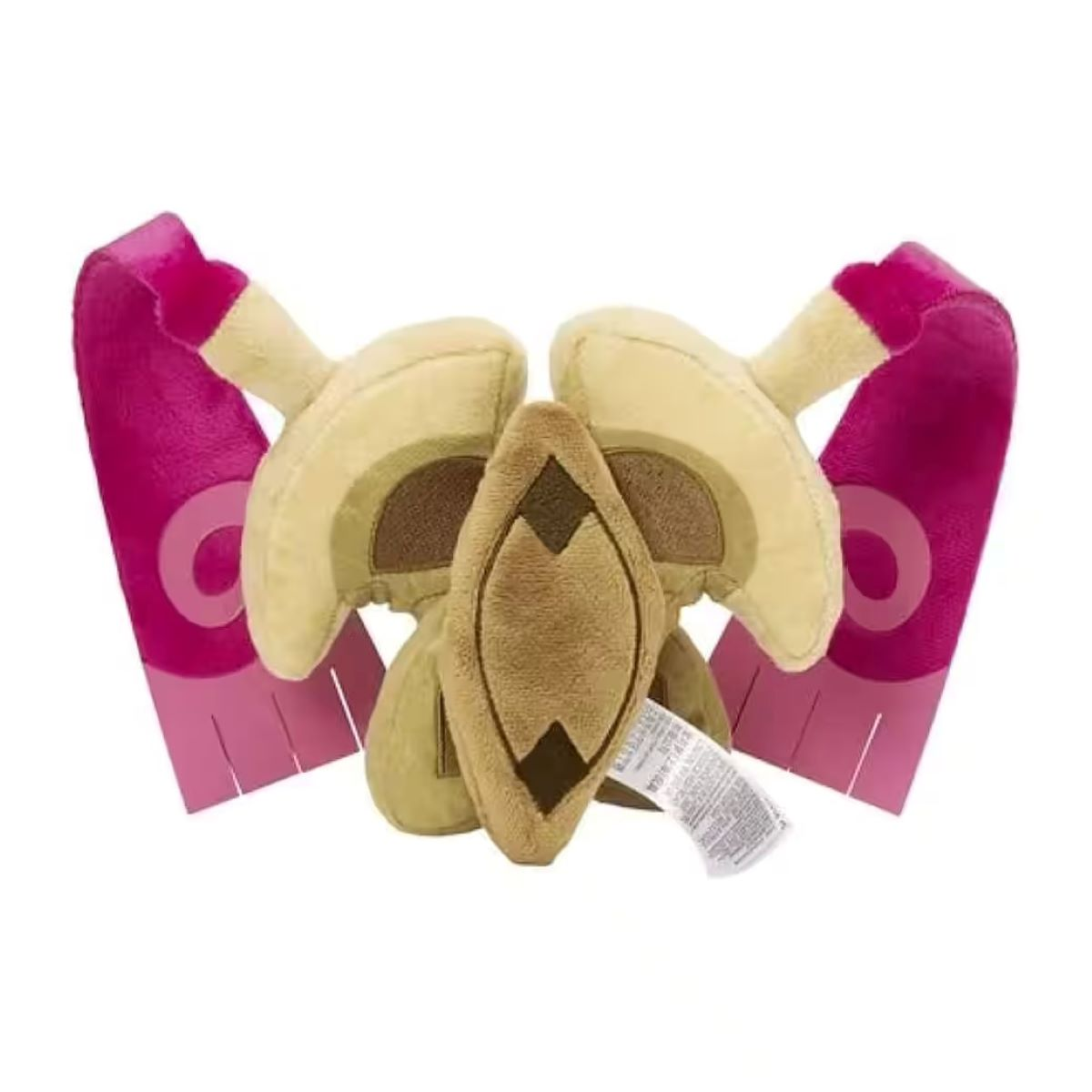 Ein Plüschtier in Form eines stilisierten Kopfes. Es hat beige, braune und rosa Elemente. Ein Etikett ist angebracht.