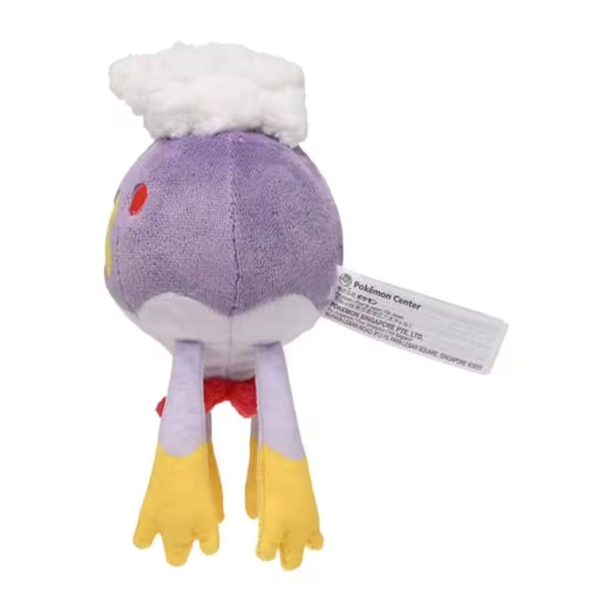 Ein Plüschtier eines lila Pokemon-Charakters mit weißem wolkenartigem Haar, roter Schleife, gelben Füßen und einem Etikett.