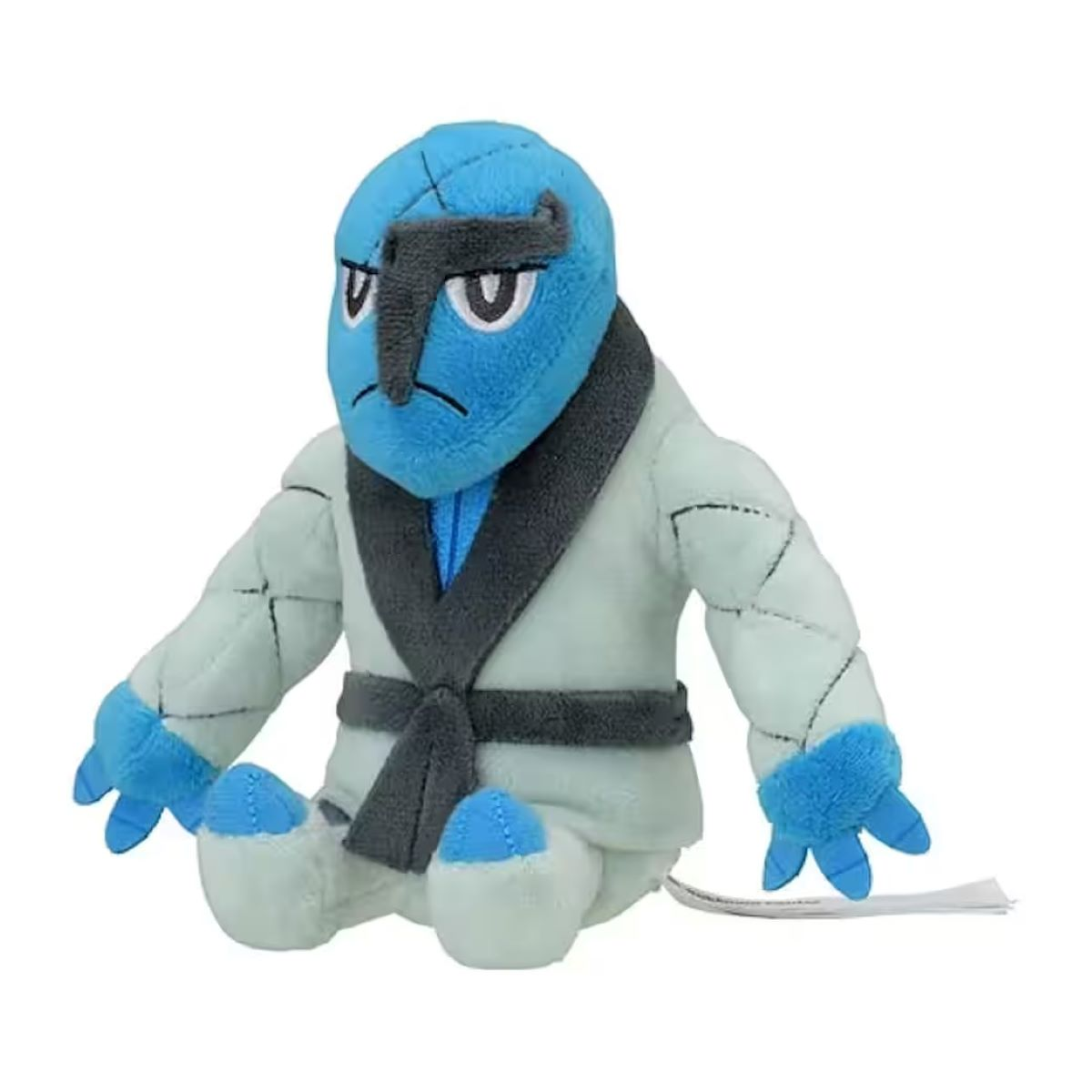 Ein Plüschtier einer Figur mit blauem Kopf und Händen, das einen weißen Robe mit grauen Akzenten trägt und auf einer weißen Oberfläche sitzt.