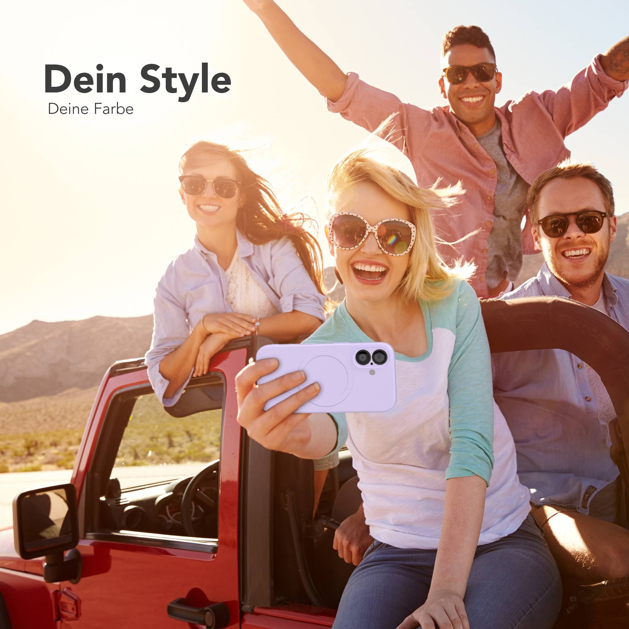 Eine Gruppe von Freunden macht ein Selfie aus einem roten Auto in der Wüste. Sie alle lächeln und tragen Sonnenbrillen.