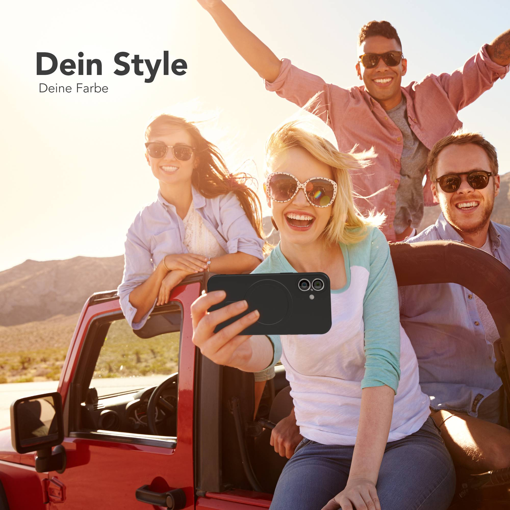 Vier Personen in einem roten Jeep machen ein Selfie. Die Person vorne hält ein Telefon und lächelt. Sonniges Wetter draußen.