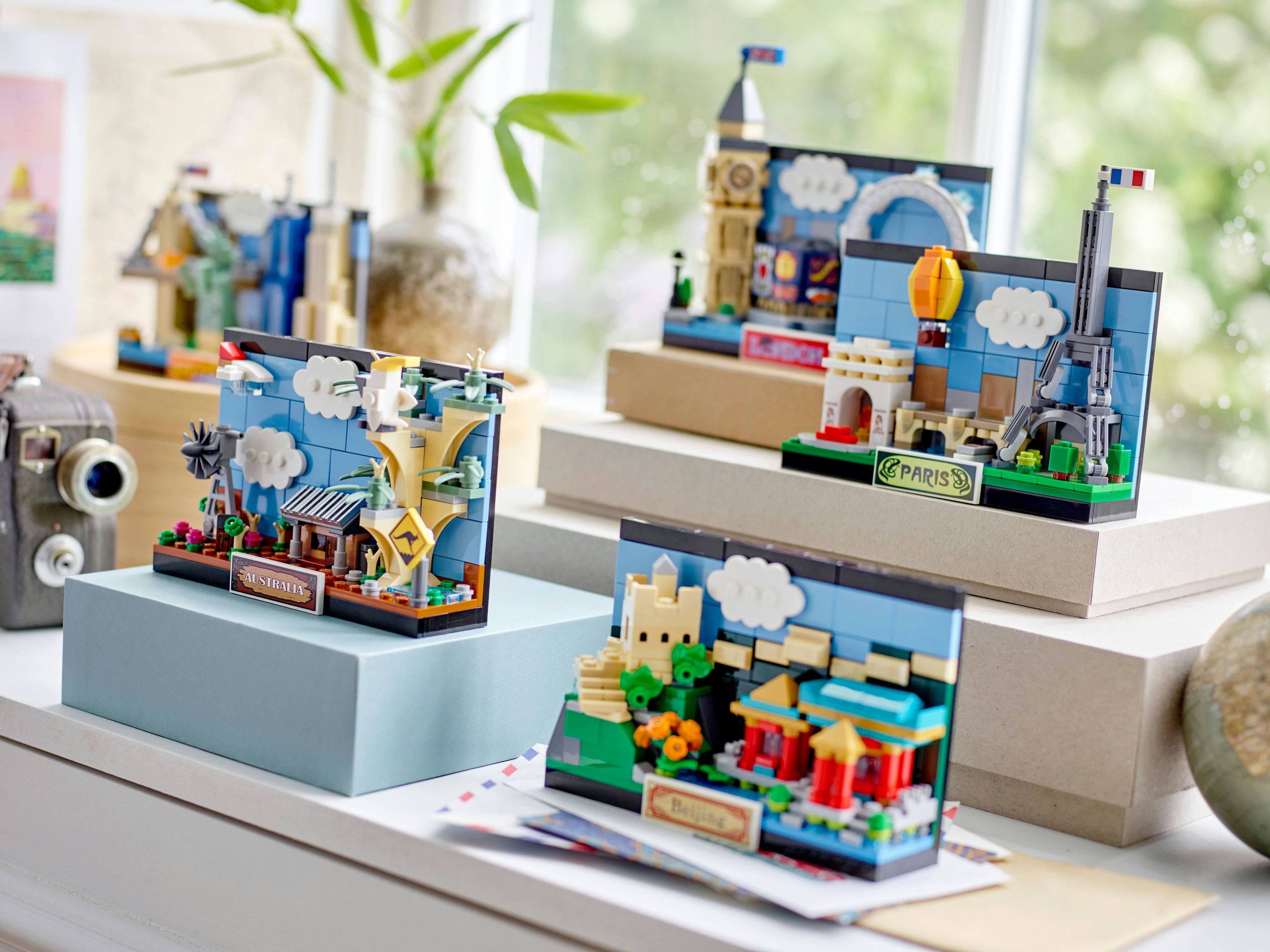 Modelli Lego di monumenti: Australia, Londra, Parigi e Pechino. Esposti su superfici bianche con una finestra sullo sfondo.