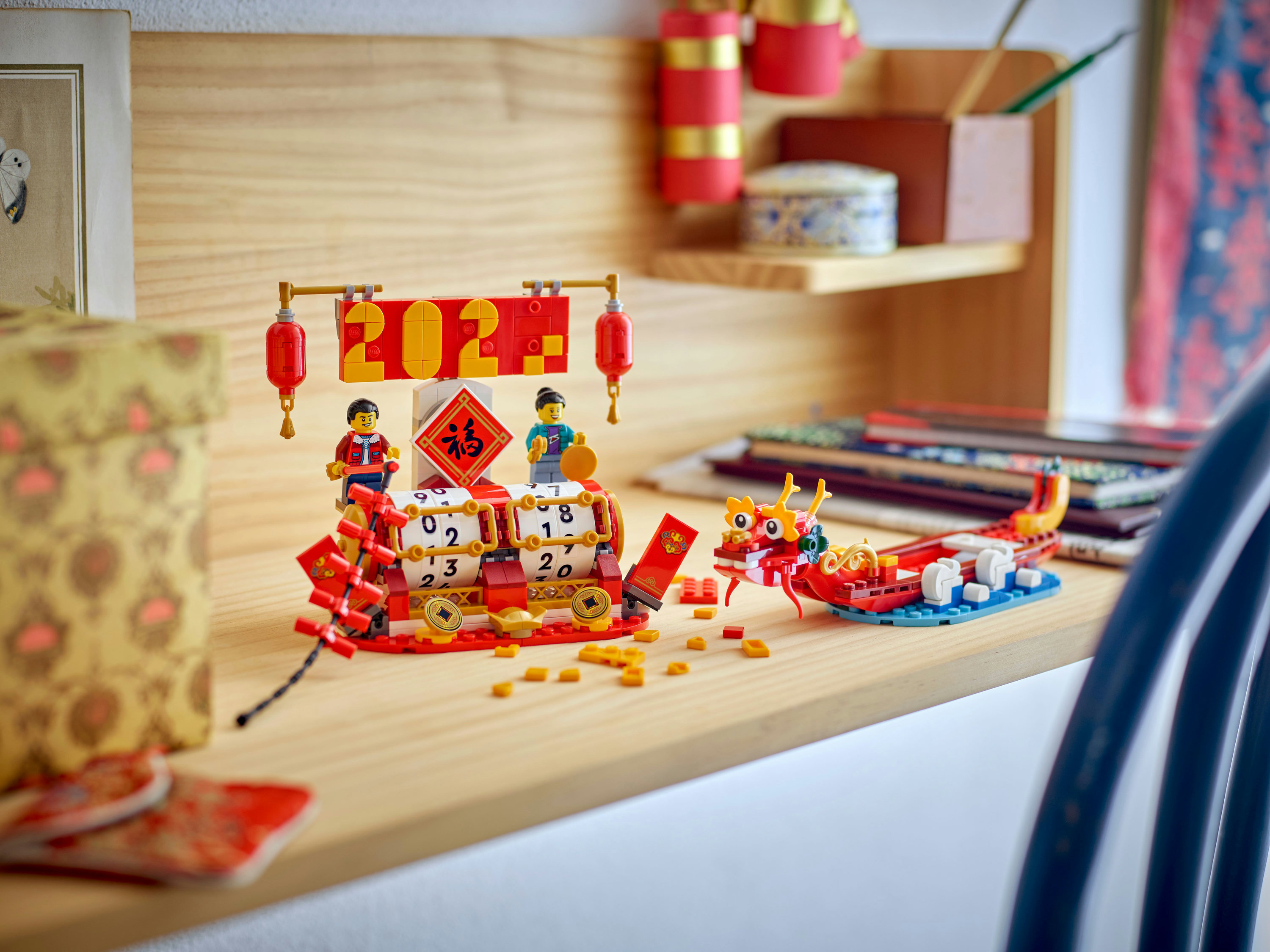 Un set LEGO del Capodanno cinese con personaggi, una barca drago e il numero 2021. Su una superficie di legno.
