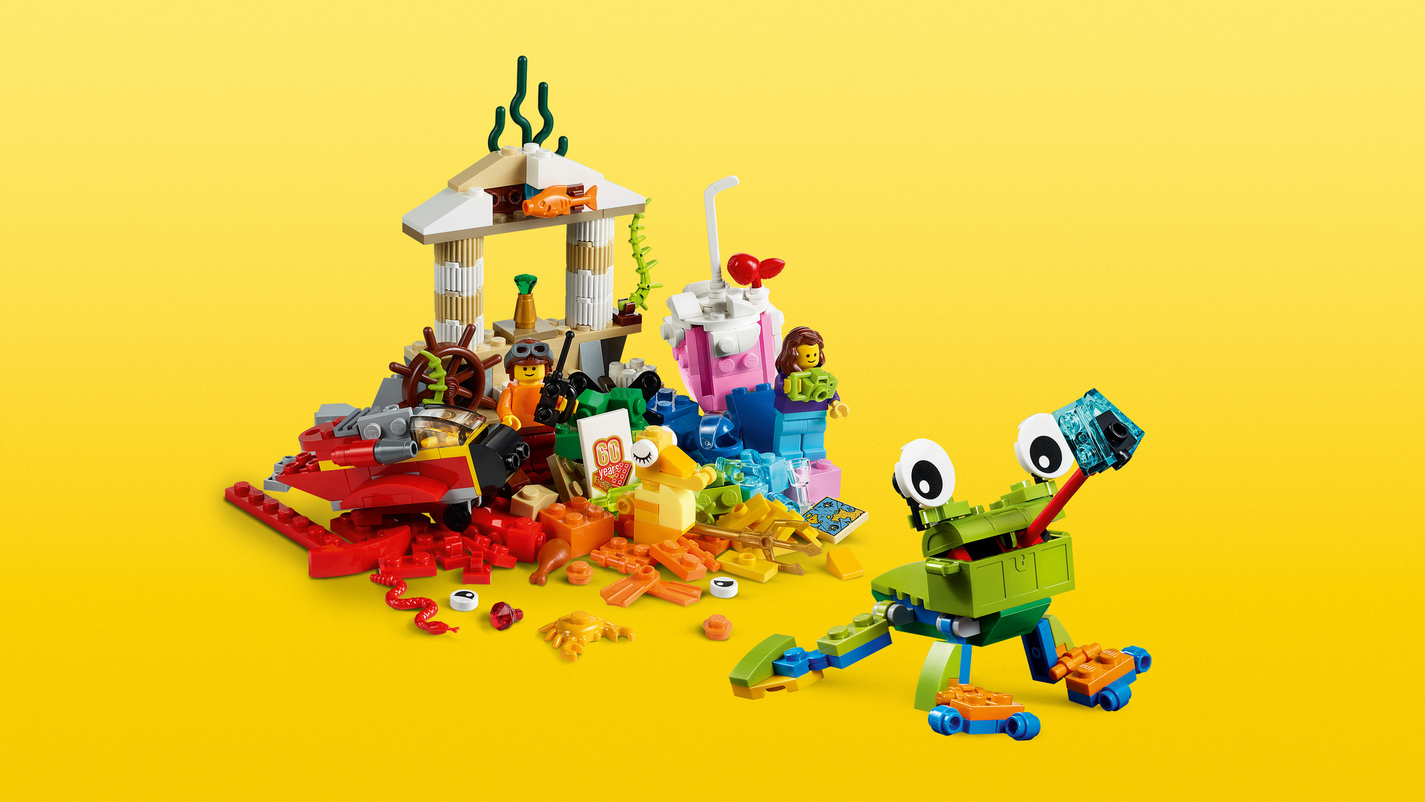 Zestaw Lego na żółtym tle. Zawiera zieloną żabę, małą świątynię i różowy napój. Zawiera różne figurki i przedmioty Lego.