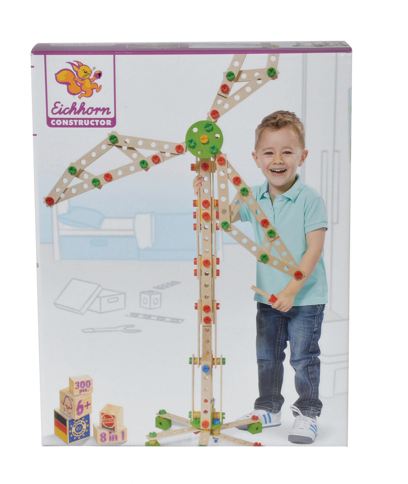 Chłopiec uśmiecha się, trzymając drewnianą zabawkę konstrukcyjną. Pudełko przedstawia zabawkę, wiatrak, z kolorowymi łącznikami.