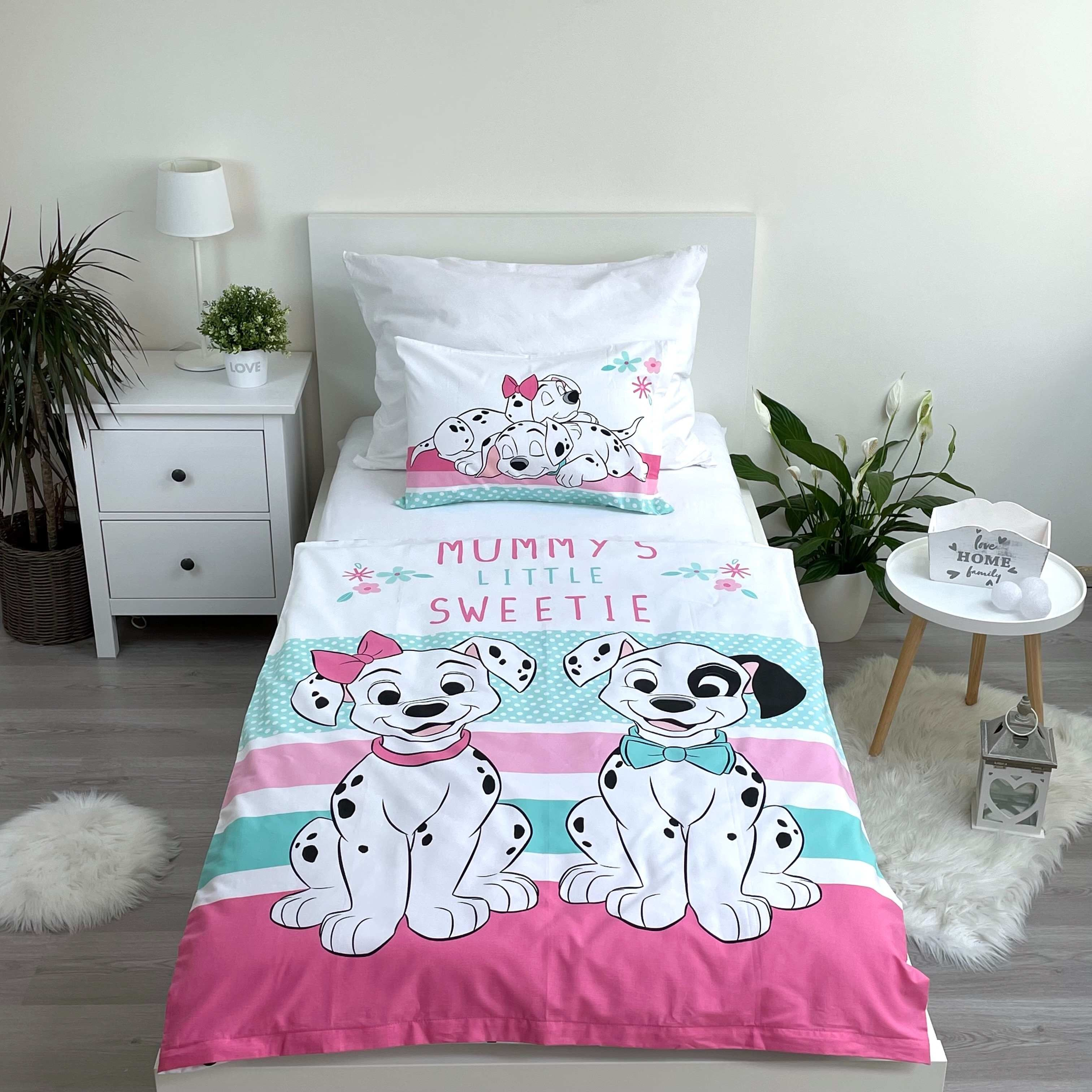 Ein Bett mit Bettwäsche mit zwei Cartoon-Dalmatinern. Weiße Wände und Möbel. Pflanzen und ein flauschiger Teppich sind ebenfalls vorhanden.