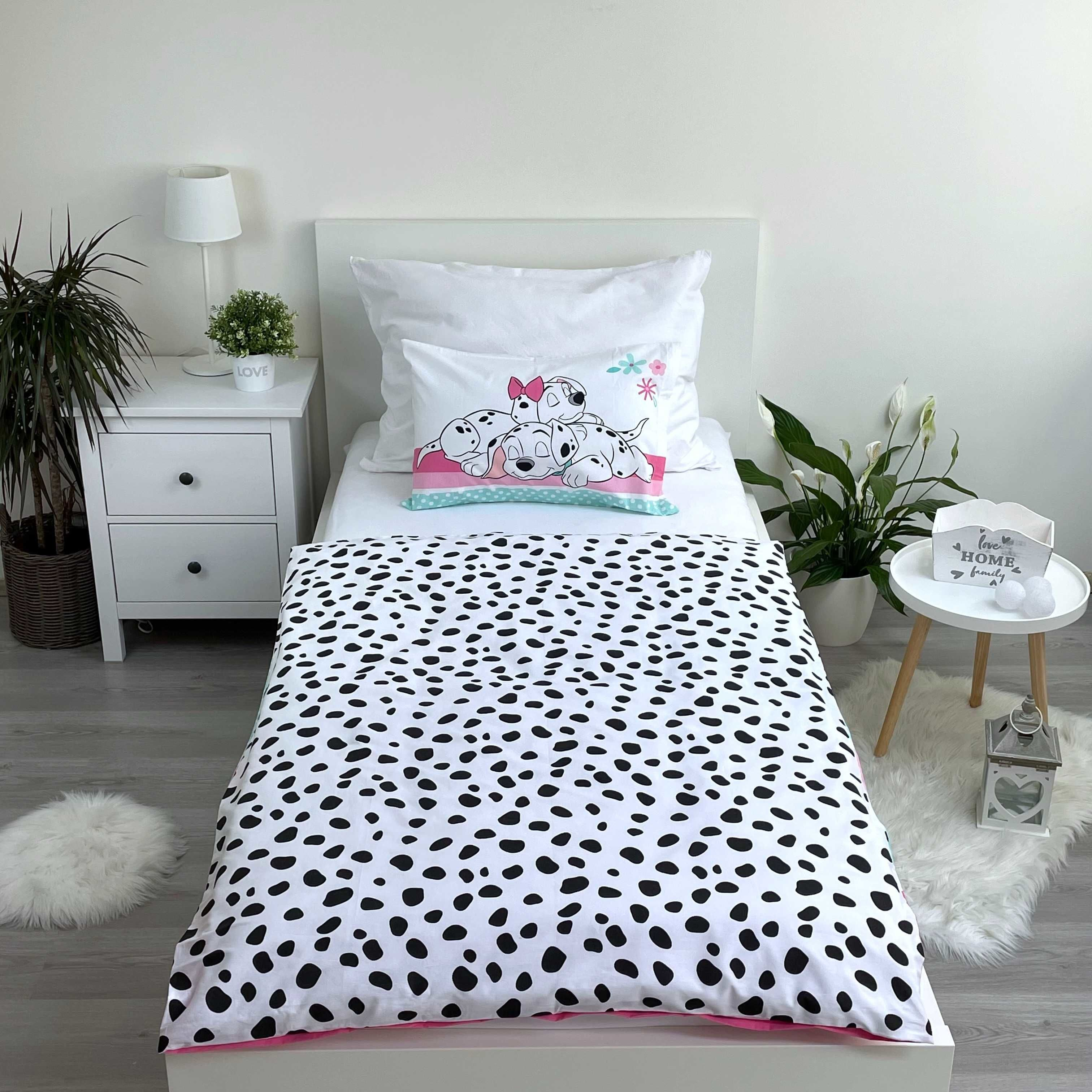 Ein Schlafzimmer mit weißem Bett, Dalmatiner-Bettwäsche, Nachttisch und Pflanzen. Das Bett hat ein Kissen mit Dalmatiner-Welpen.